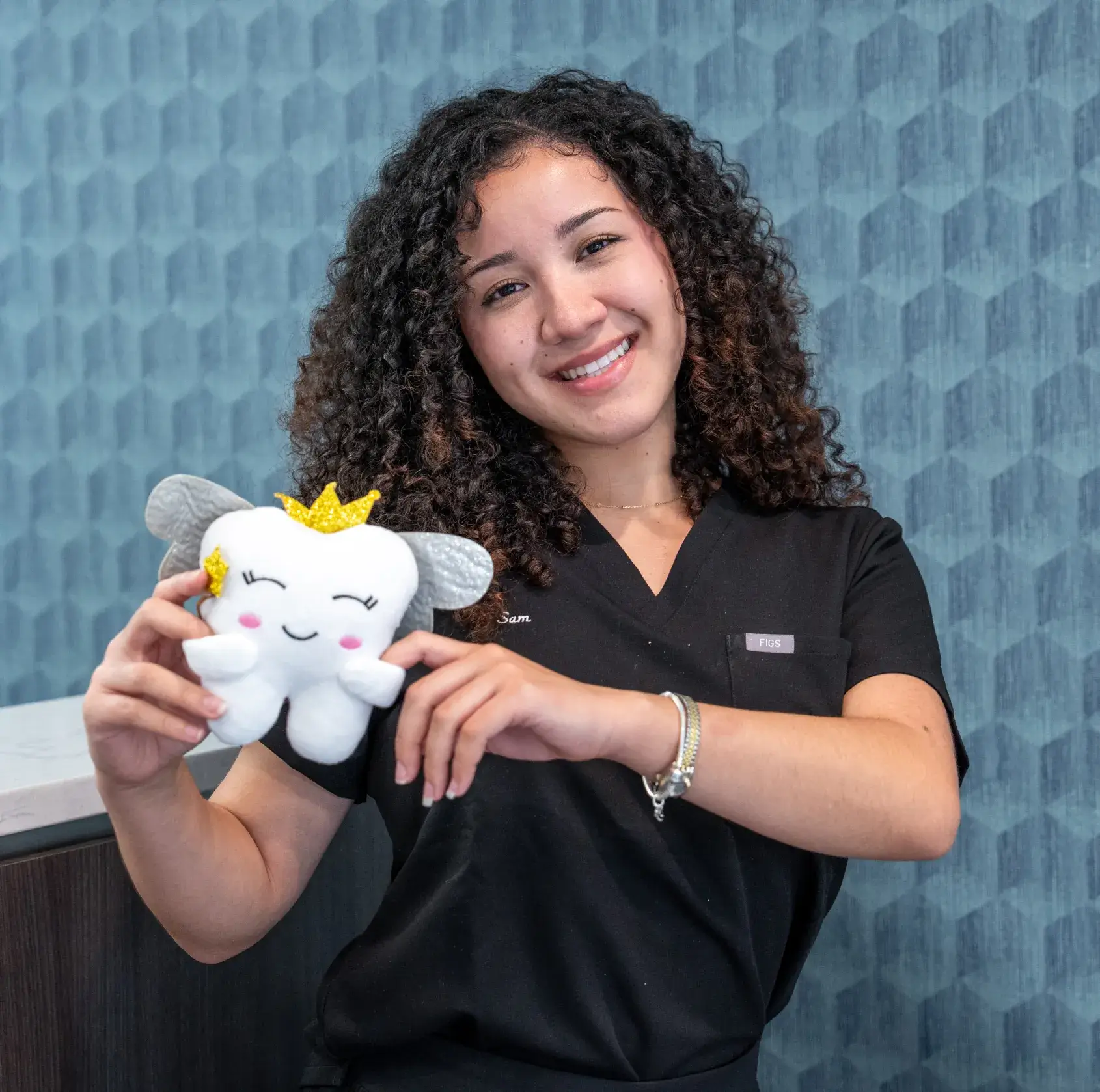A dentist holds a large toothbrush, smiling with a seated patient holding a red dental tray.