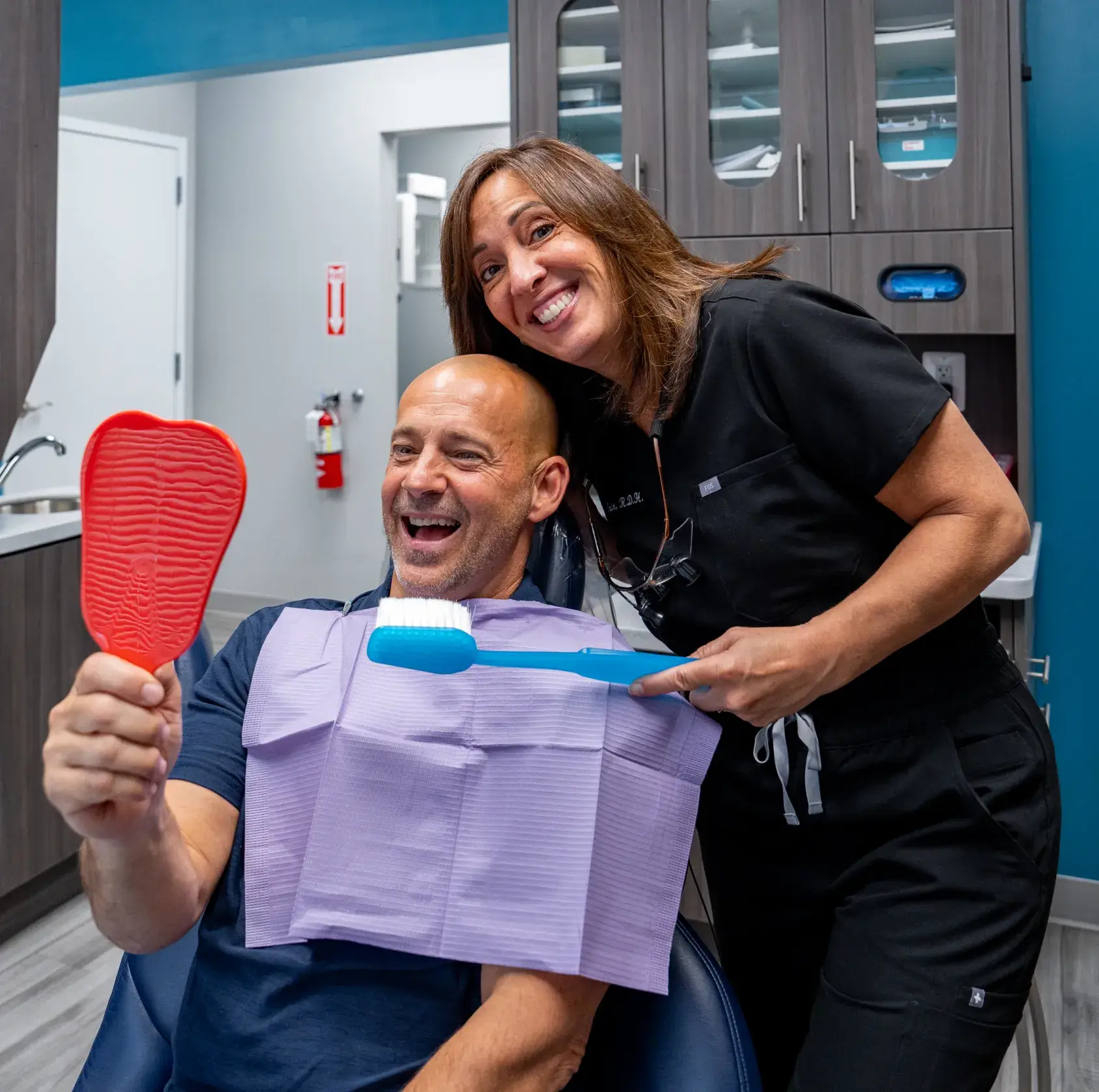 Two dental professionals examine a patient lying in a dentist chair in a clinic.