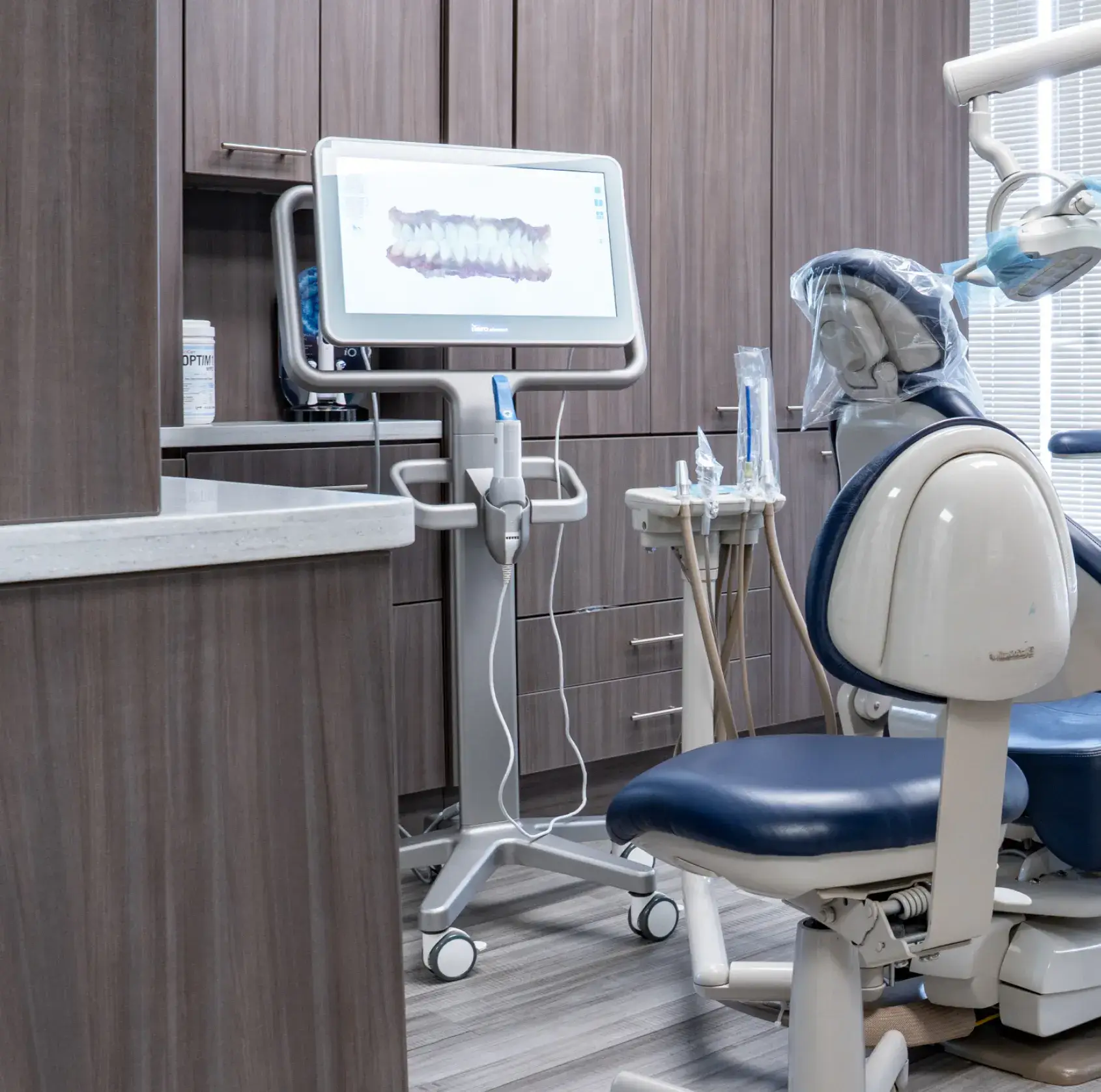Dentist office showing a dental chair and a large screen displaying a dental scan.