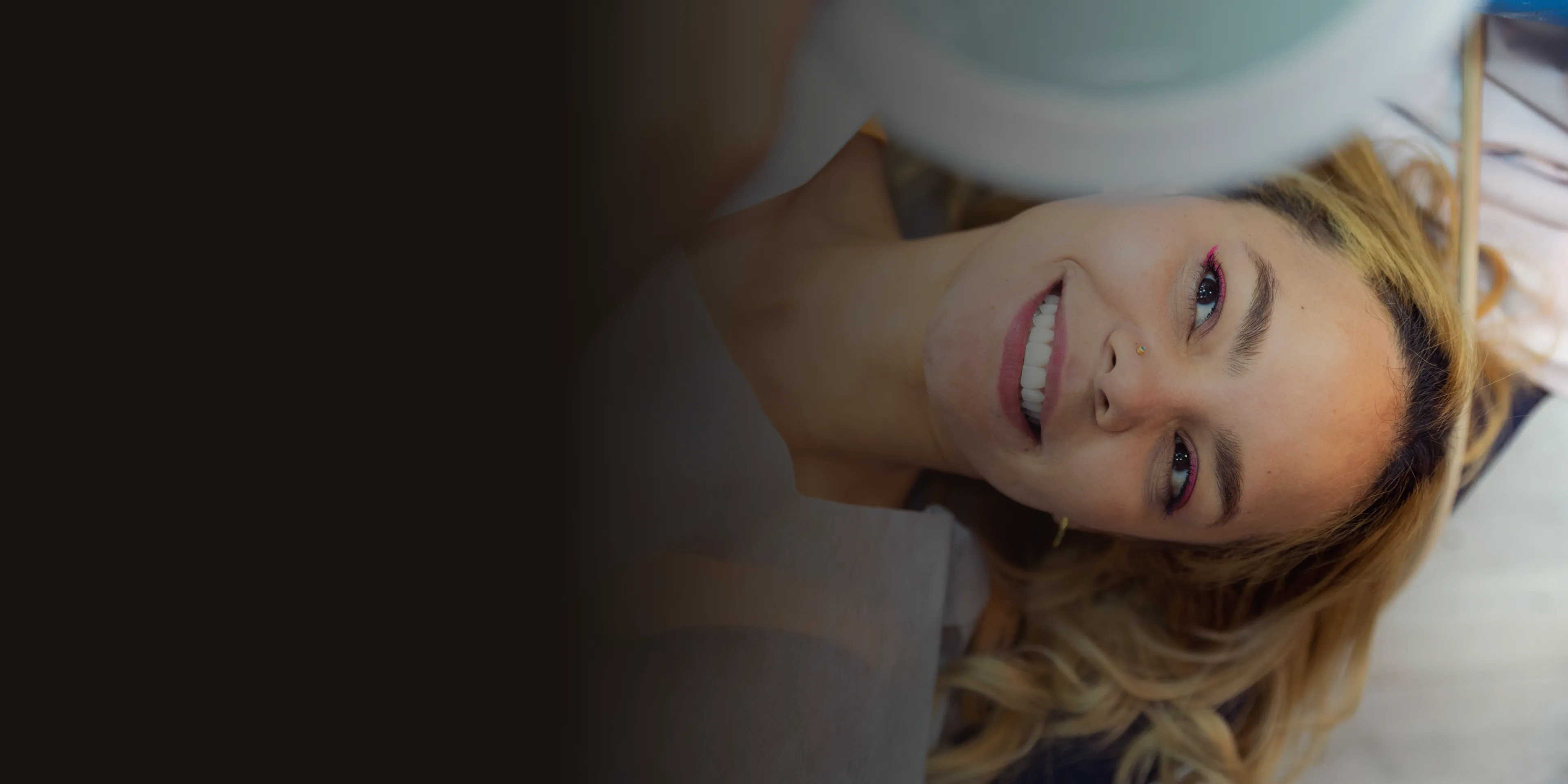 Woman smiling while lying down, with a defocused area on the left.