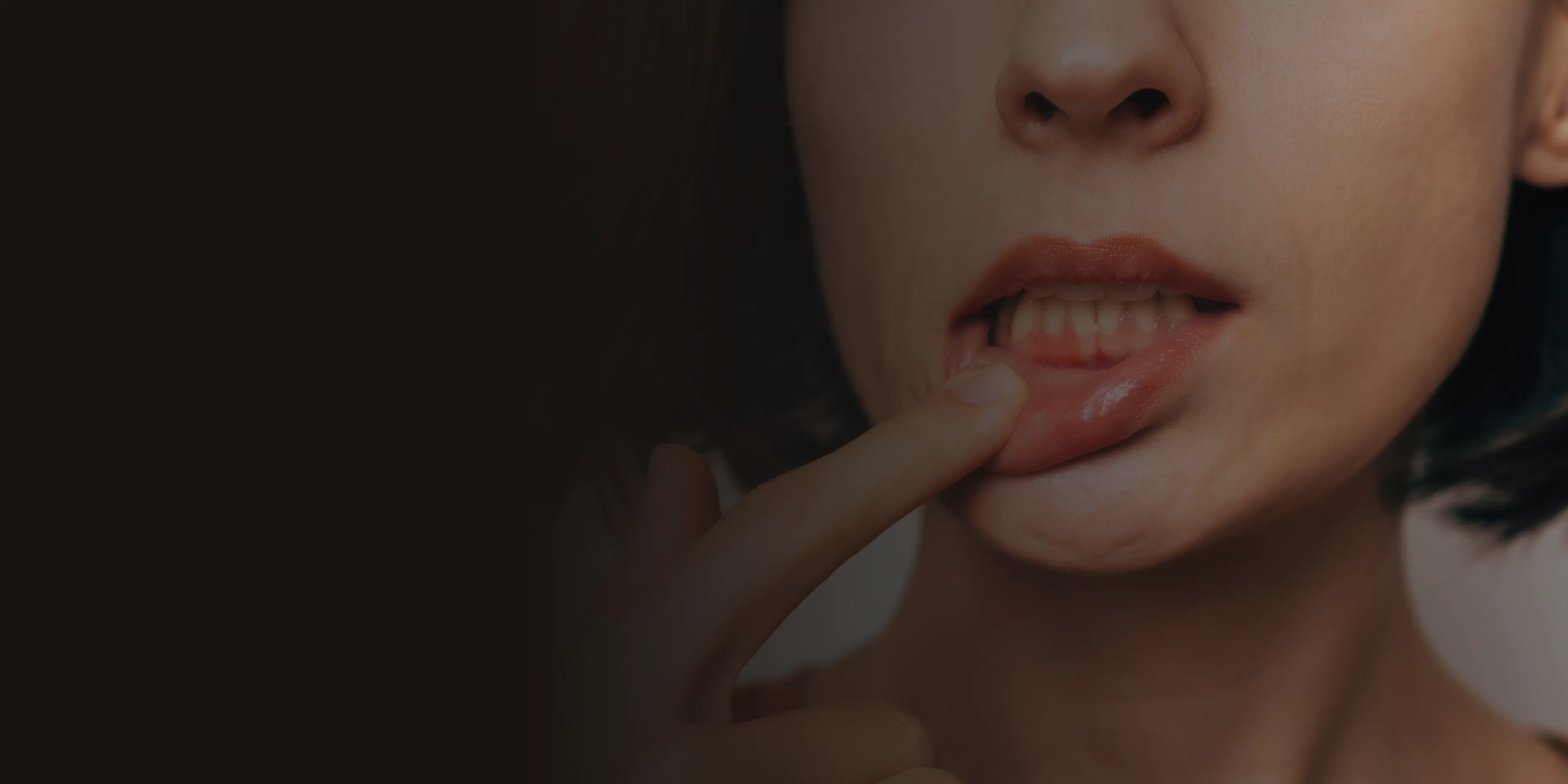 A person gently pulls their lower lip down with a finger, showing their teeth.
