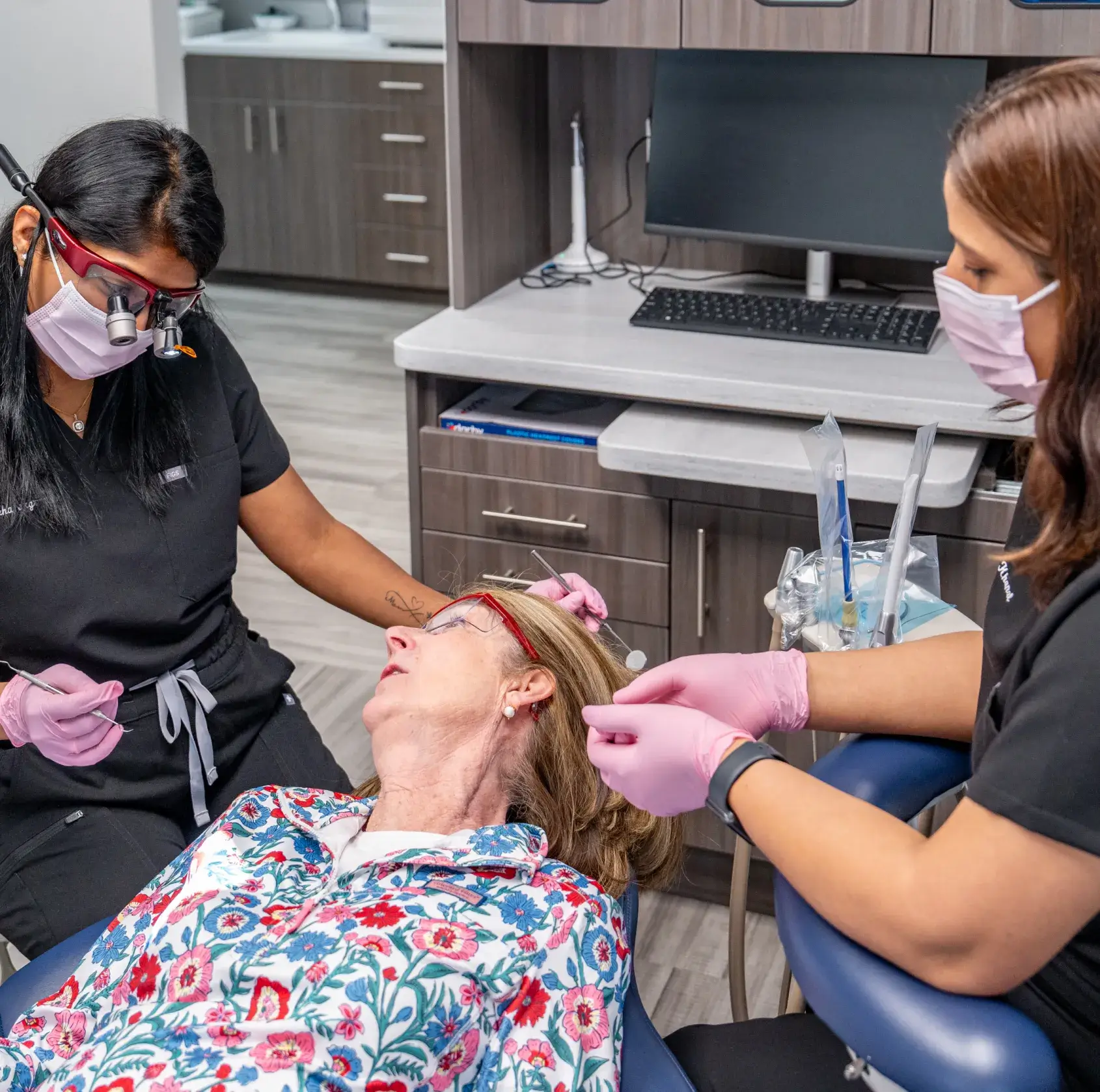 Two dental professionals examine a patient lying in a dental chair.