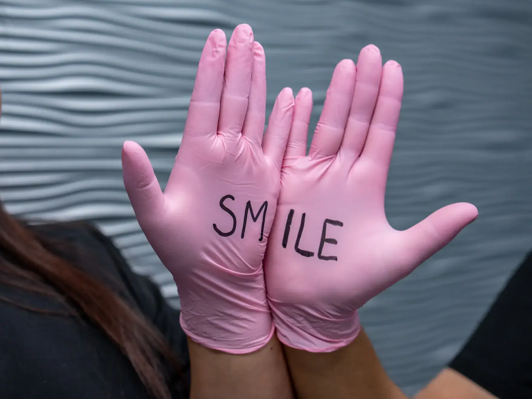 Two hands wearing pink gloves with the word "SMILE" written across the palms.