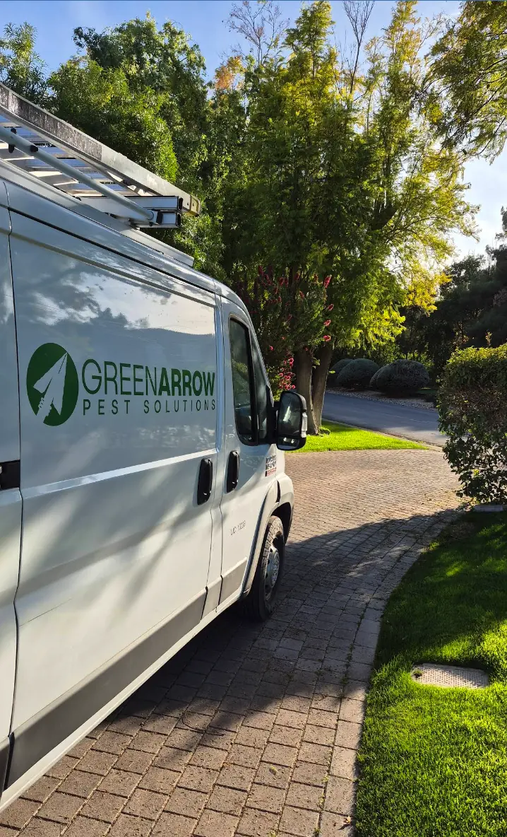 Green Arrow Pest Solutions service van parked outside a home