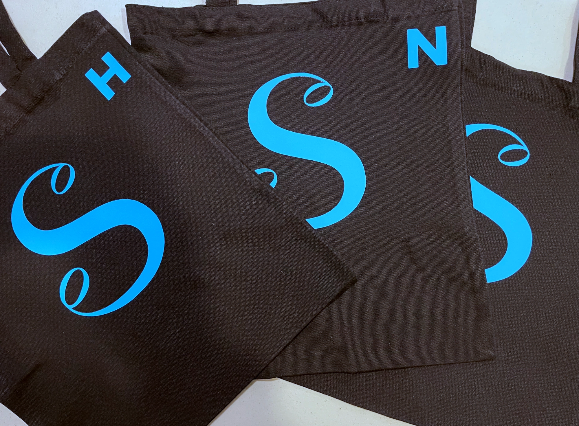 Three black bags with blue "S" logo and smaller initials