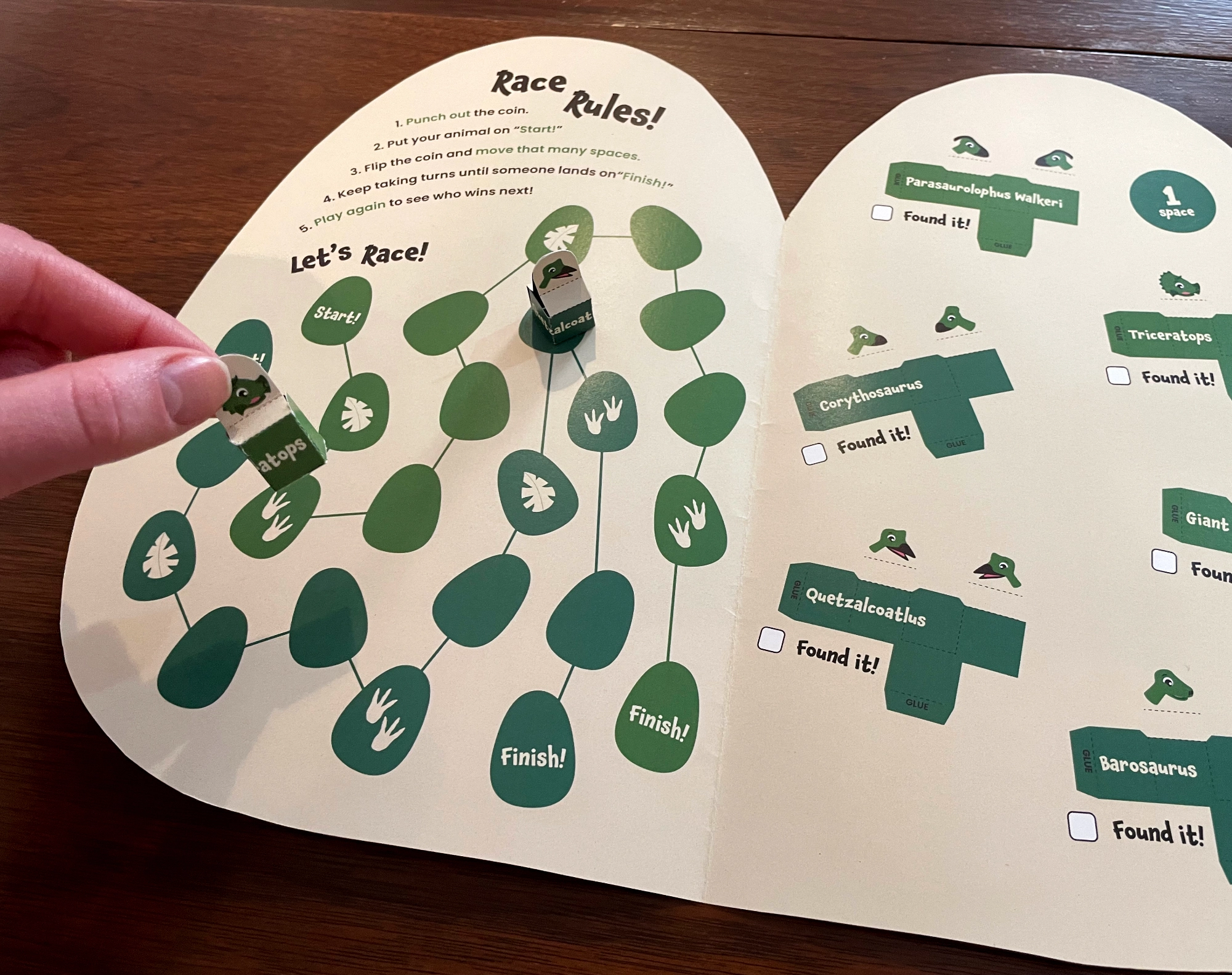 Dinosaur handout inside with racing game and hand playing with game pieces