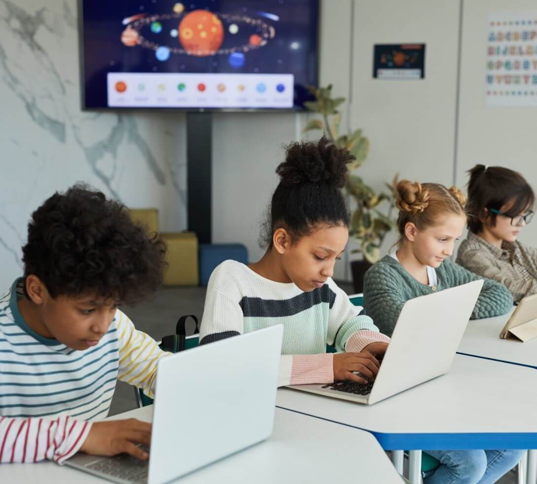 Group of kids working on devices.  Notably, they aren't asking for tech help because they devices work!