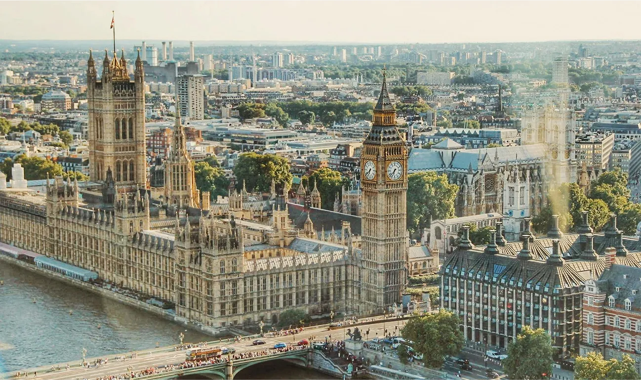 Aerial view of the Palace of Westminster and Big Ben in London, United Kingdom, with the River Thames and cityscape in the background.