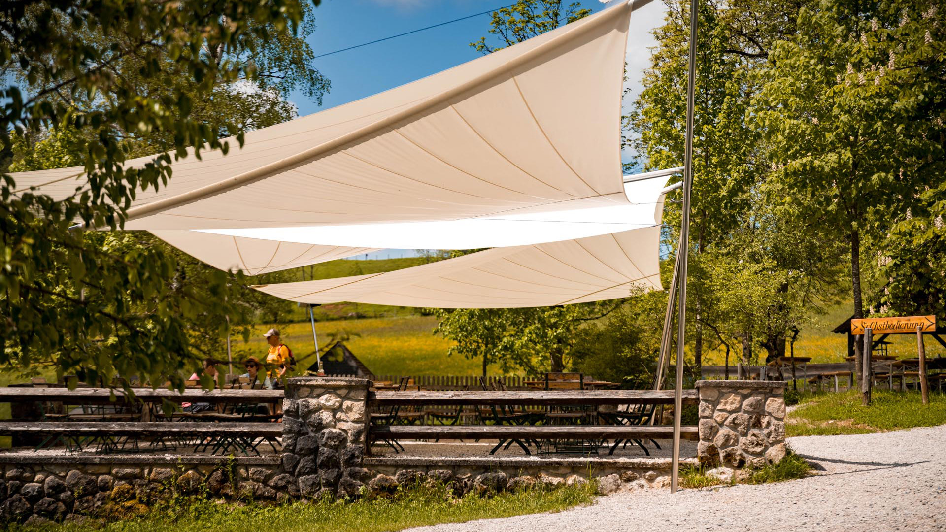 Mit den drei SunSquare Sonnensegelanlagen - Modell SQK-I - ist der Gastgarten am idylischen Gleinkersee bestens gerüstet, um müde und hungrige Wanderer und Freizeitsportler vor zu viel Sonne oder auch Regen zu schützen. Die drei Segel haben in Summe eine Tuchfläche von rund 165 m², gefertigt als Strahlensegel mit Präventivlatte.
So lässt es sich ausruhen und genießen. Ein tolles Projekt von Star-Roll Sun Shade Trading GmbH.
