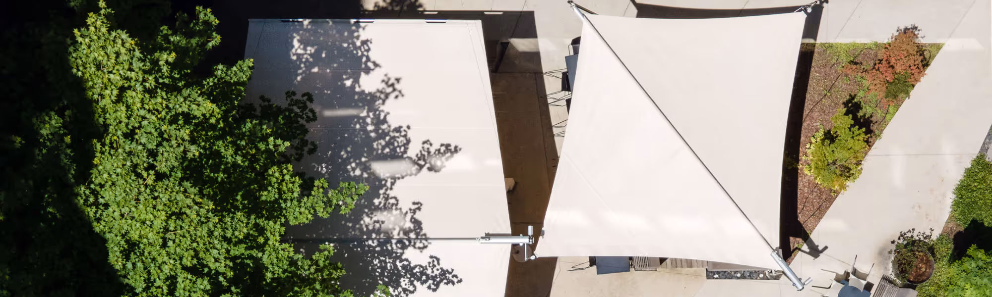 Ein Projekt in einem Innenhof aus der Luft fotografiert. Man sieht ein beidseitiges Rechteck-Segel und eine SunSquare Kompensator-Anlage.