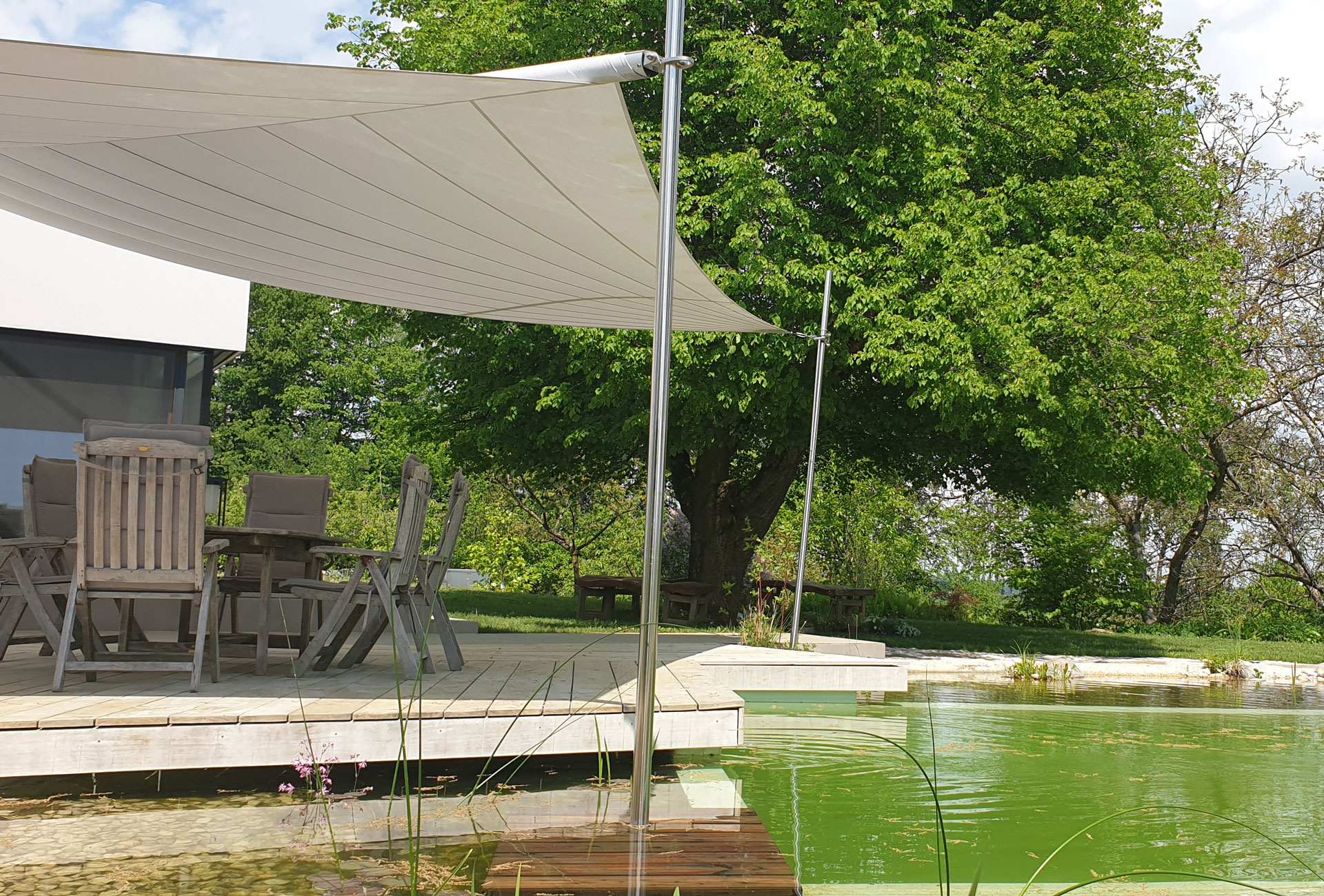 Eine SunSquare Stütze, die aus einem Schwimmteich ragt, unterstreicht die hohe Güte des verwendeten Stützenmaterials.