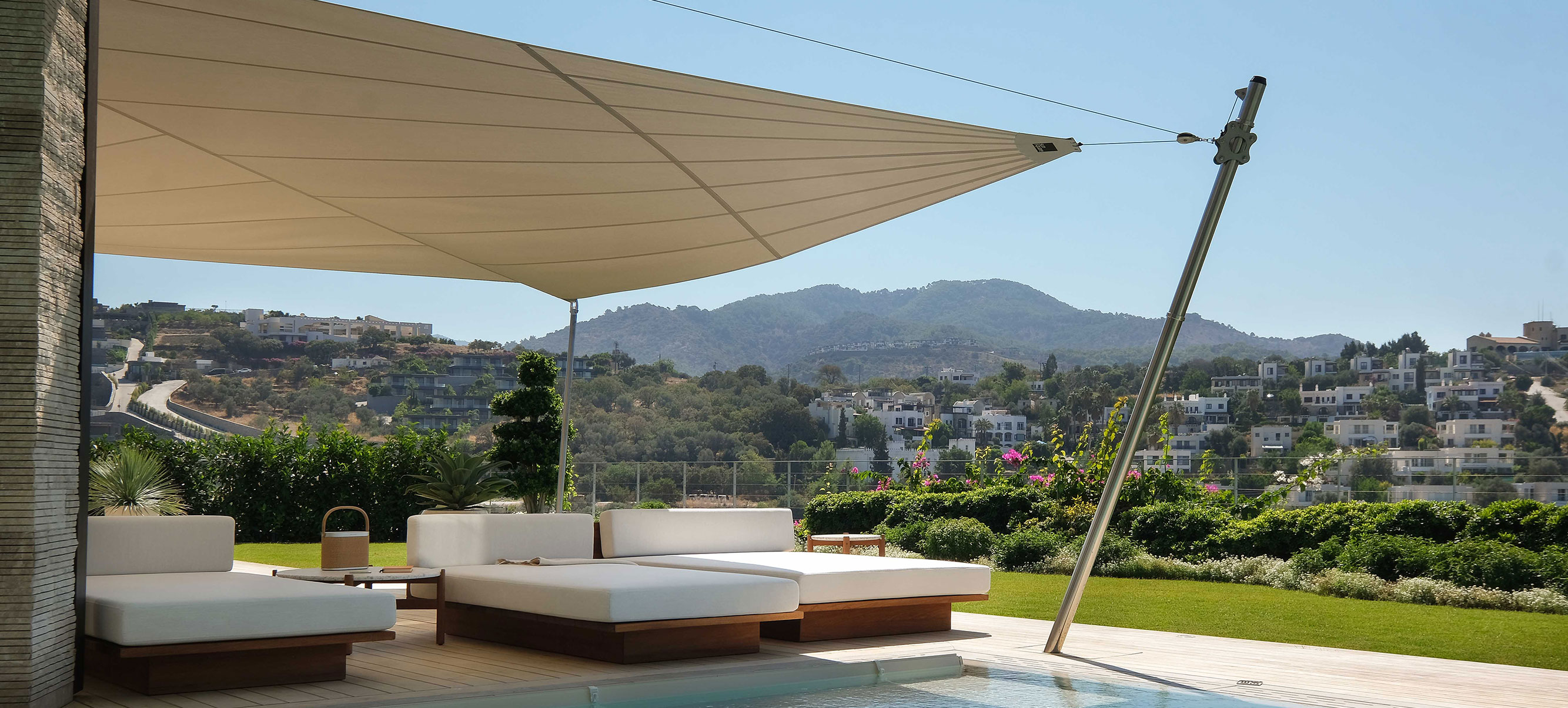 Ein elektrischer Höhenversteller an einem Segelende einer SunSquare Anlage in der Türkei. Stimmungsvolle Umgebung mit Pool und Sonnenliegen.