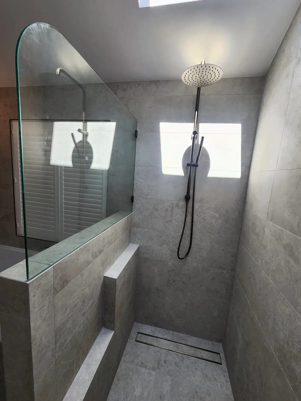 Open shower with a tiled ledge, linear drain and custom glass screen in a Craigburn Farm bathroom