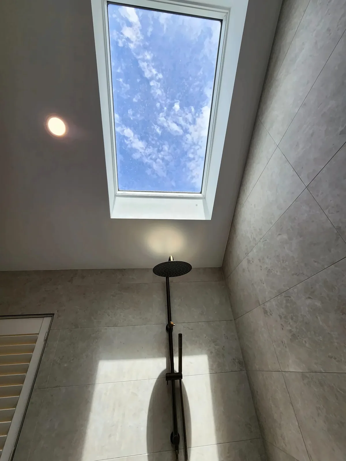 Large Velux skylight above an open shower with a black rail shower and grey tiles, Dunsford St, Craigburn Farm