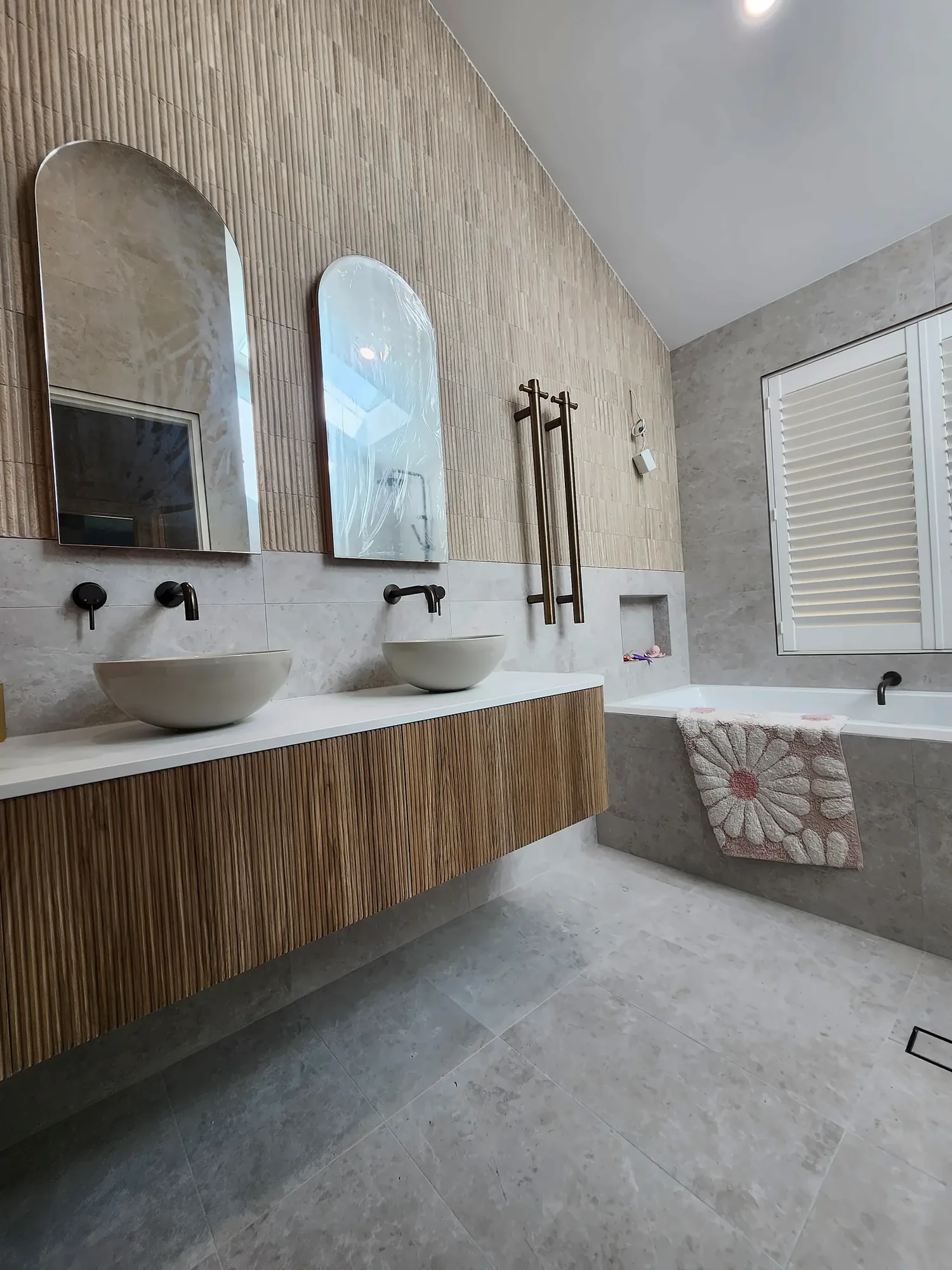 Craigburn Farm bathroom with fluted timber floating vanity, twin vessel basins, arched mirrors, shower niche and bath