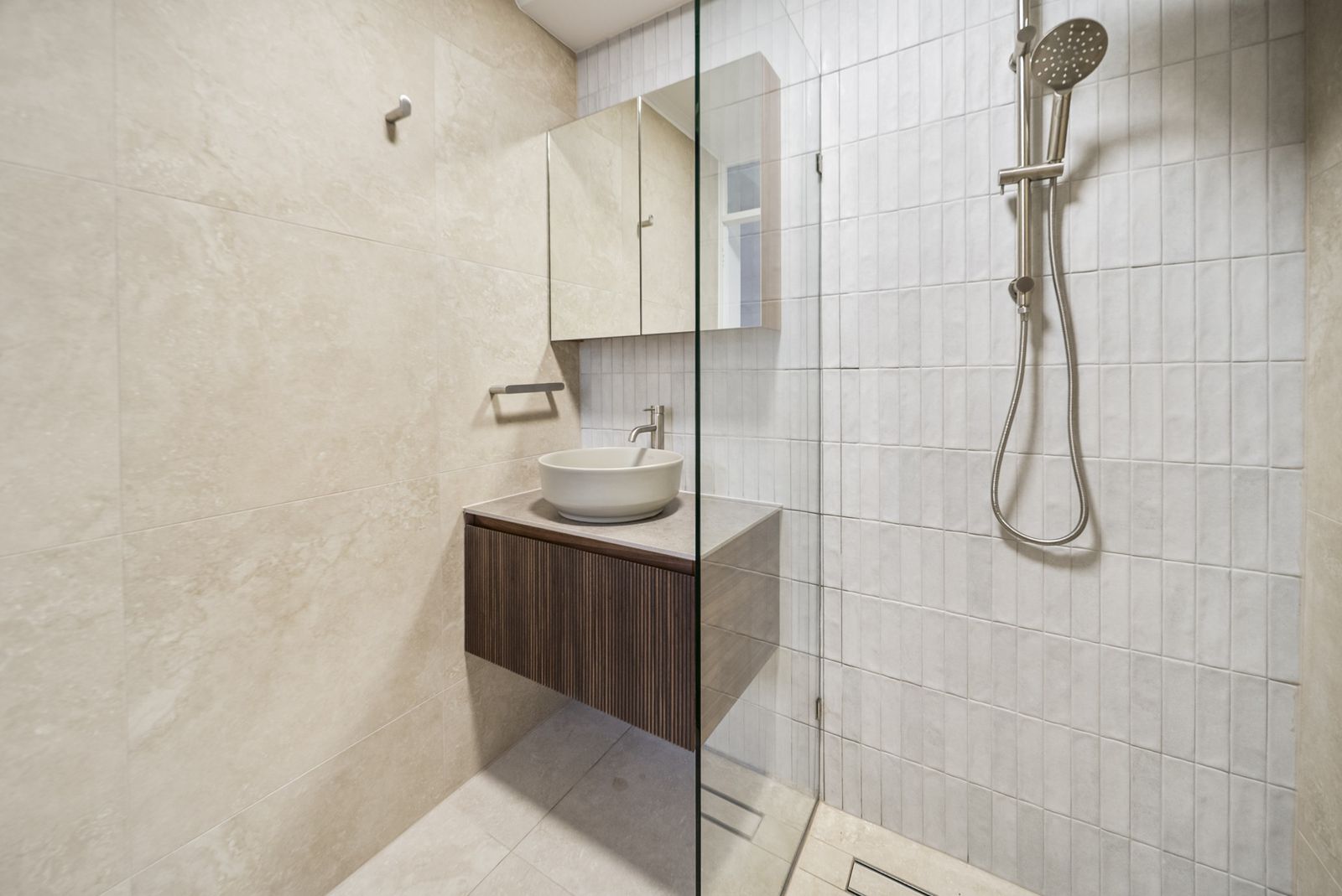 Walk-in shower with vertical tiles beside a timber vanity and above-counter basin, Angas St, Adelaide