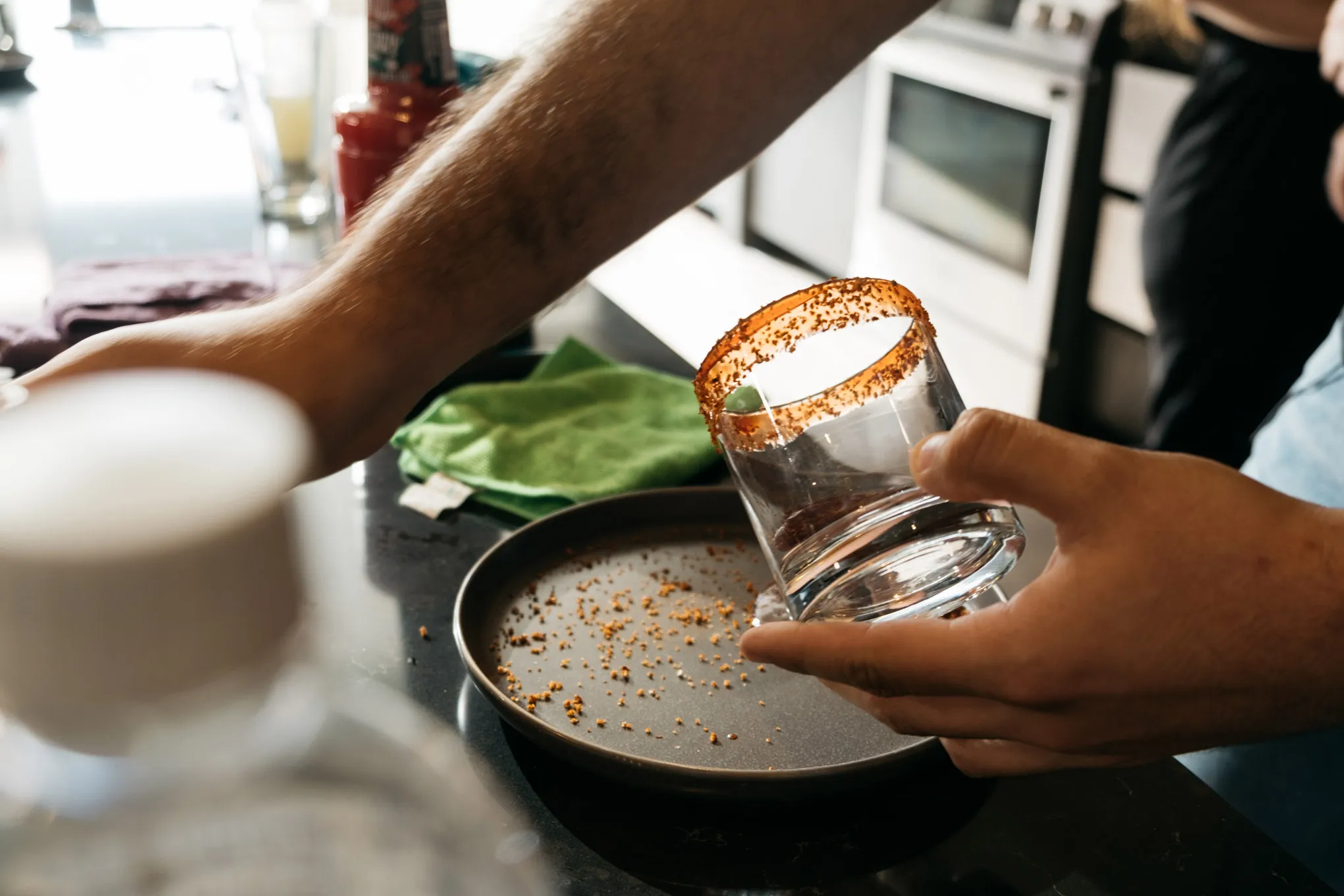 A person decorating the rim of a drinking glass with food items.