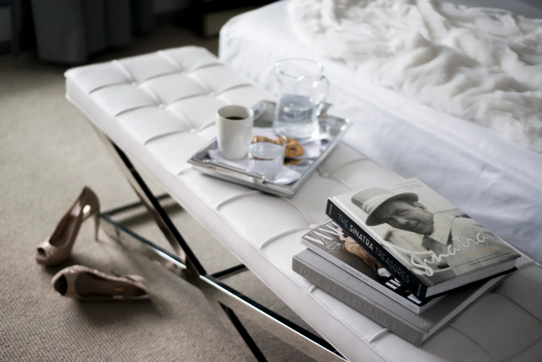 Cushioned bench stool holding items like a small pile of books and a drink tray.