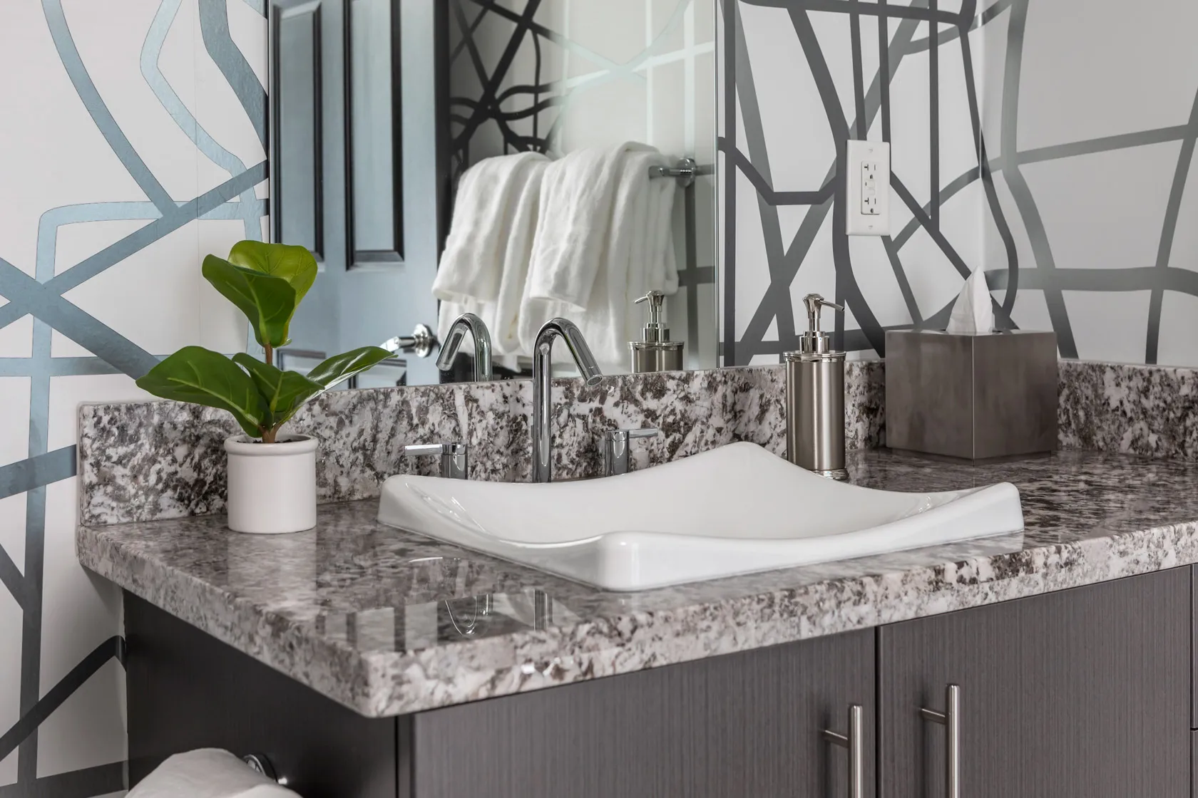 Marble sink and mirror reflecting decorated towel rack.