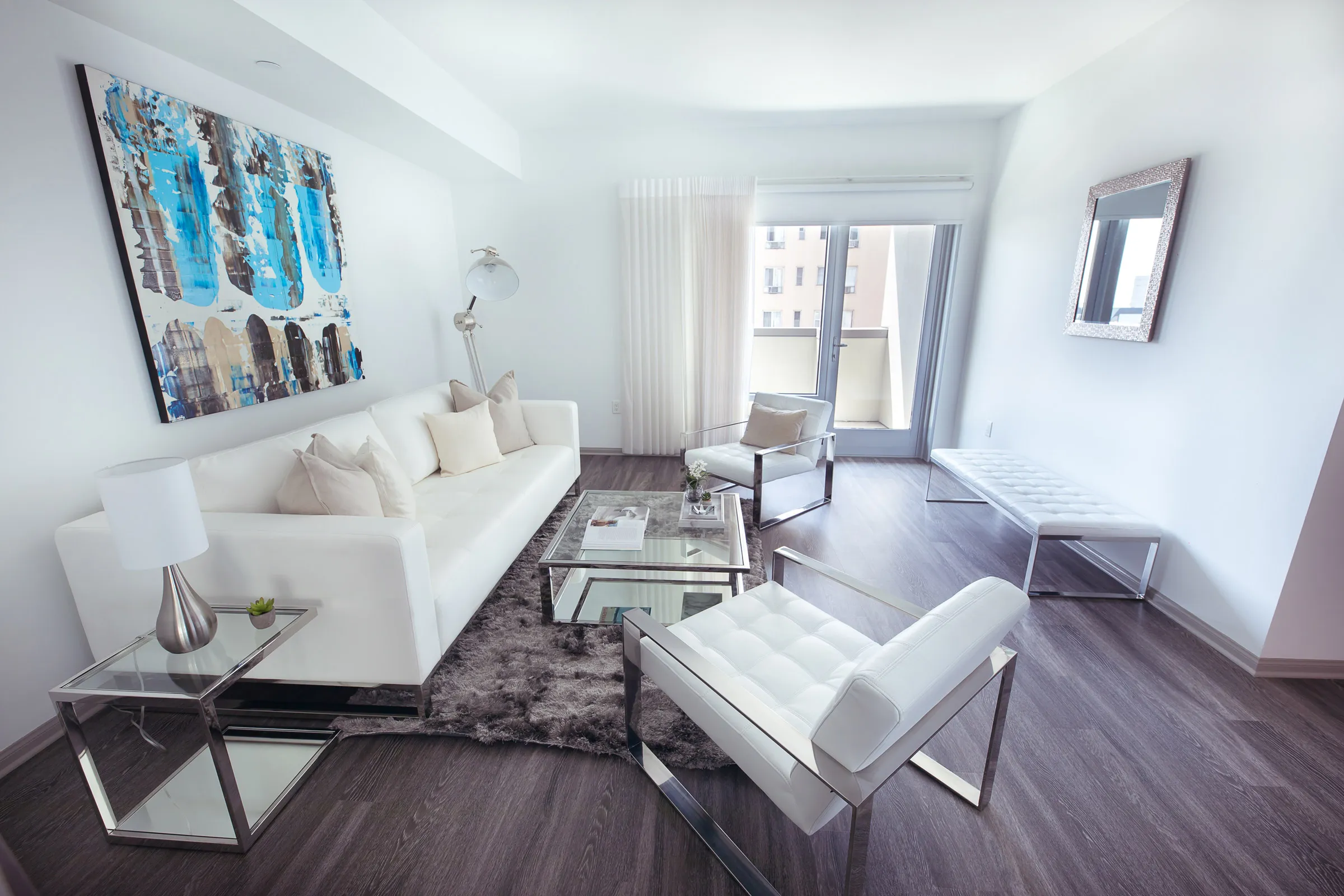 Small glass communal table surrounded by white, single-person, cushioned seats.