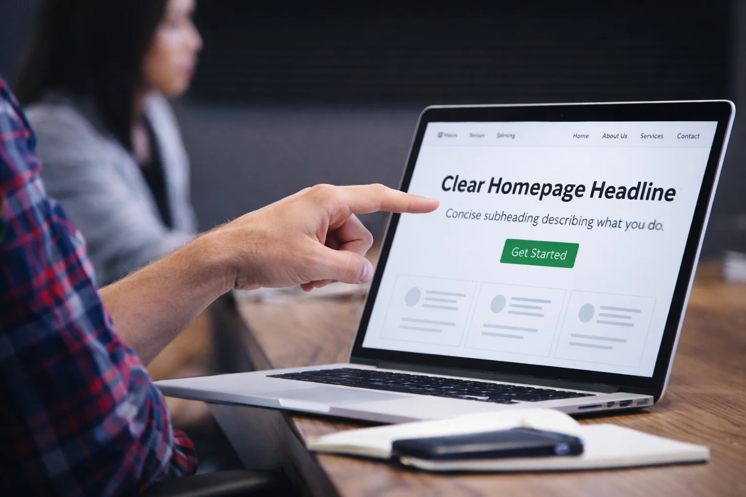 A small team reviewing a website homepage layout on a laptop, focusing on improving clarity, structure, and conversion.