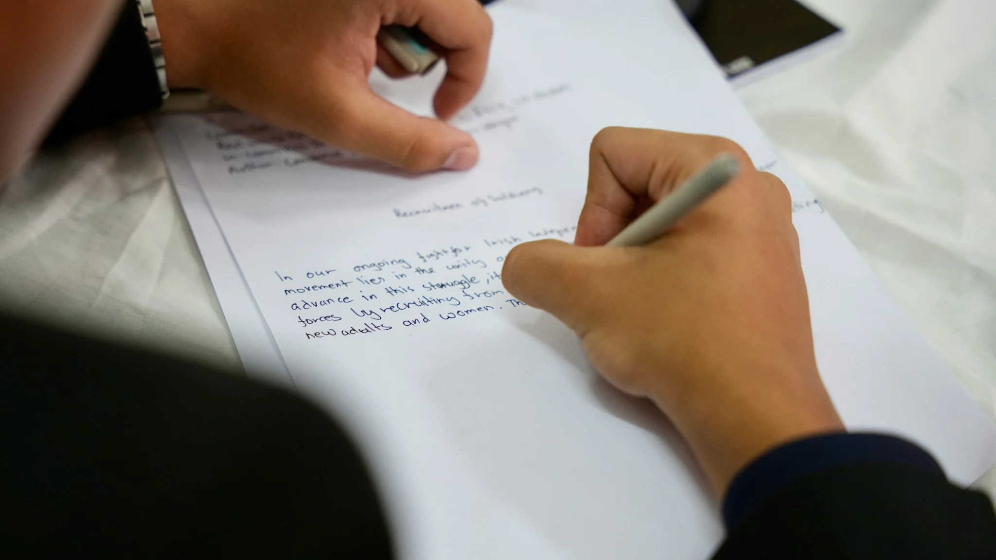 Close-up of a person writing website copy by hand on a printed draft, reviewing and refining messaging for a small business website.