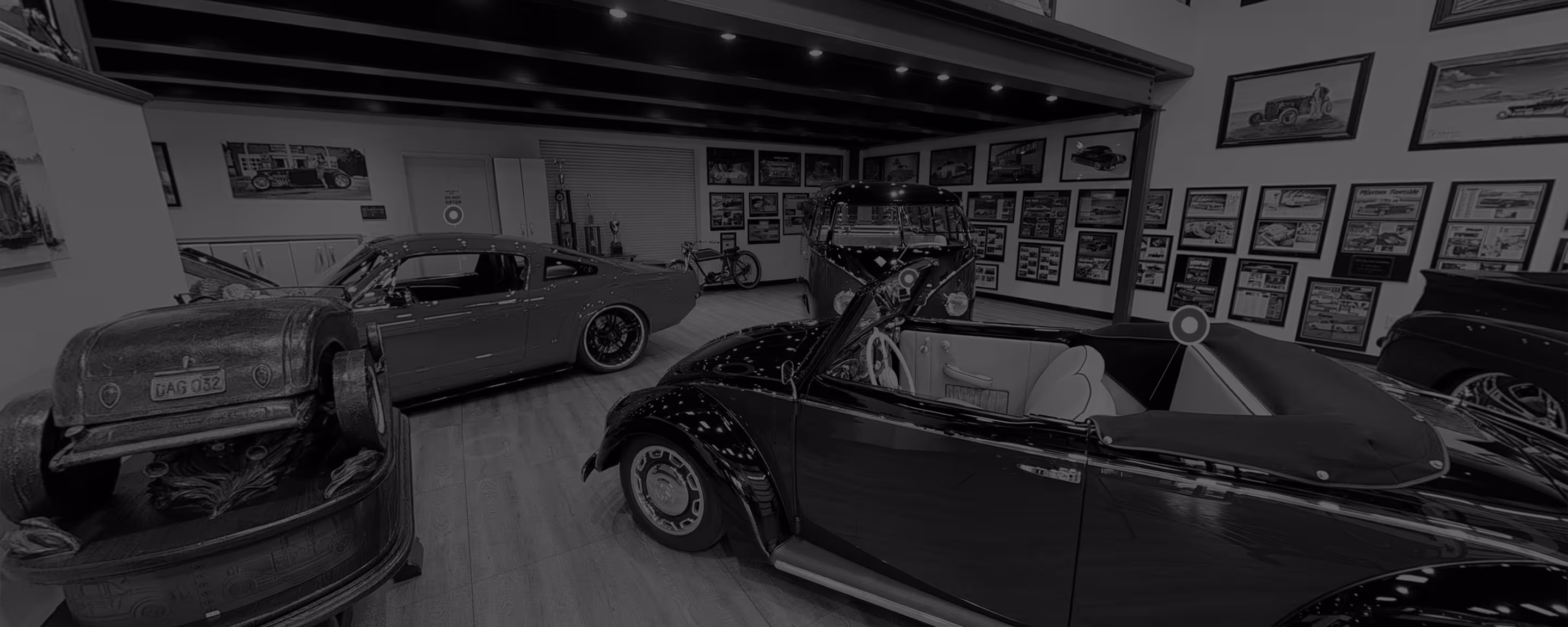 Classic car showroom featuring a convertible Volkswagen Beetle, a modern custom muscle car, vintage car artwork, and display cases.