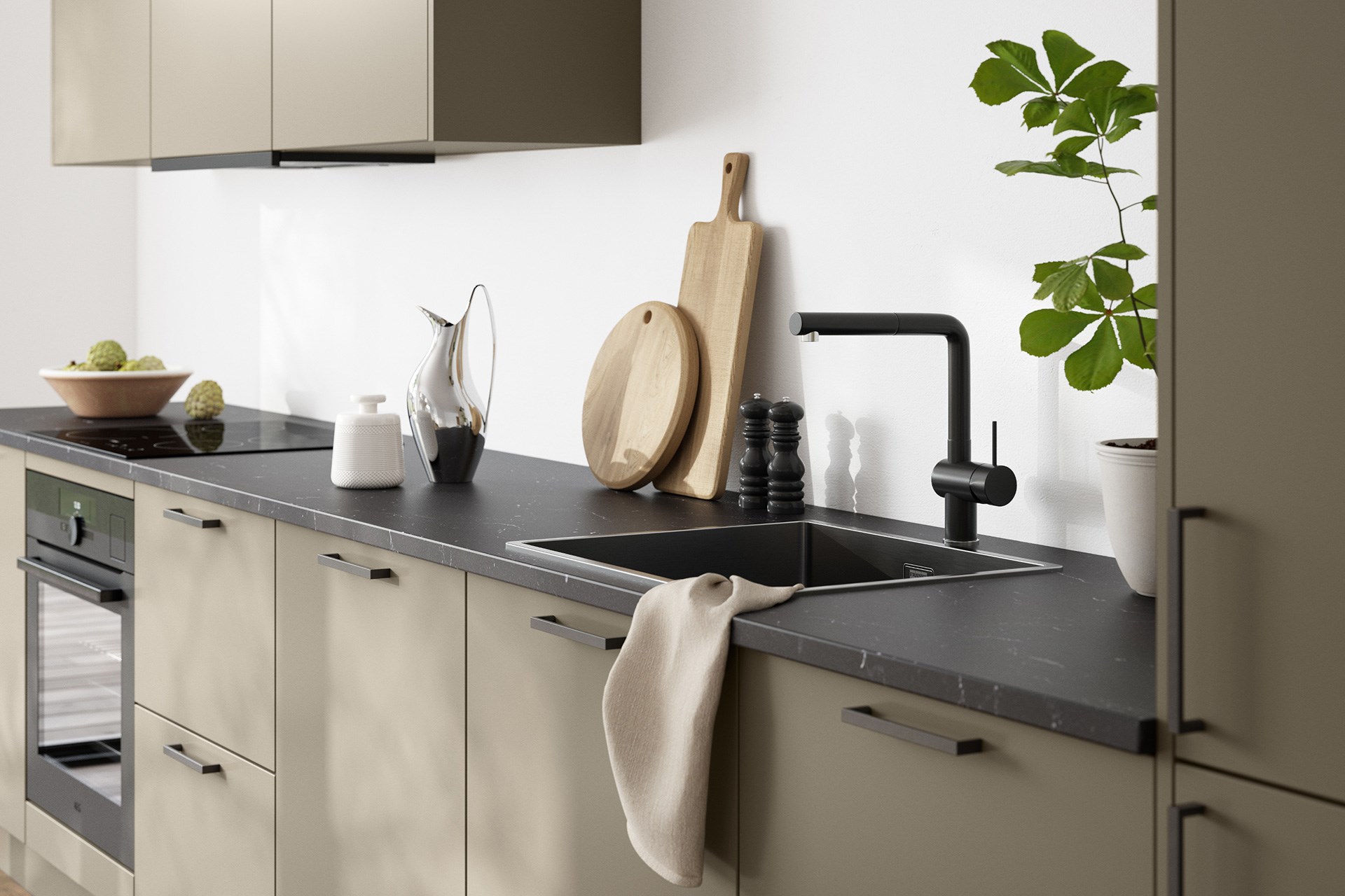 Moderne kjøkken med beige fronter, mørk benkeplate, sort kran og vask, skjærebrett og grønn plante.