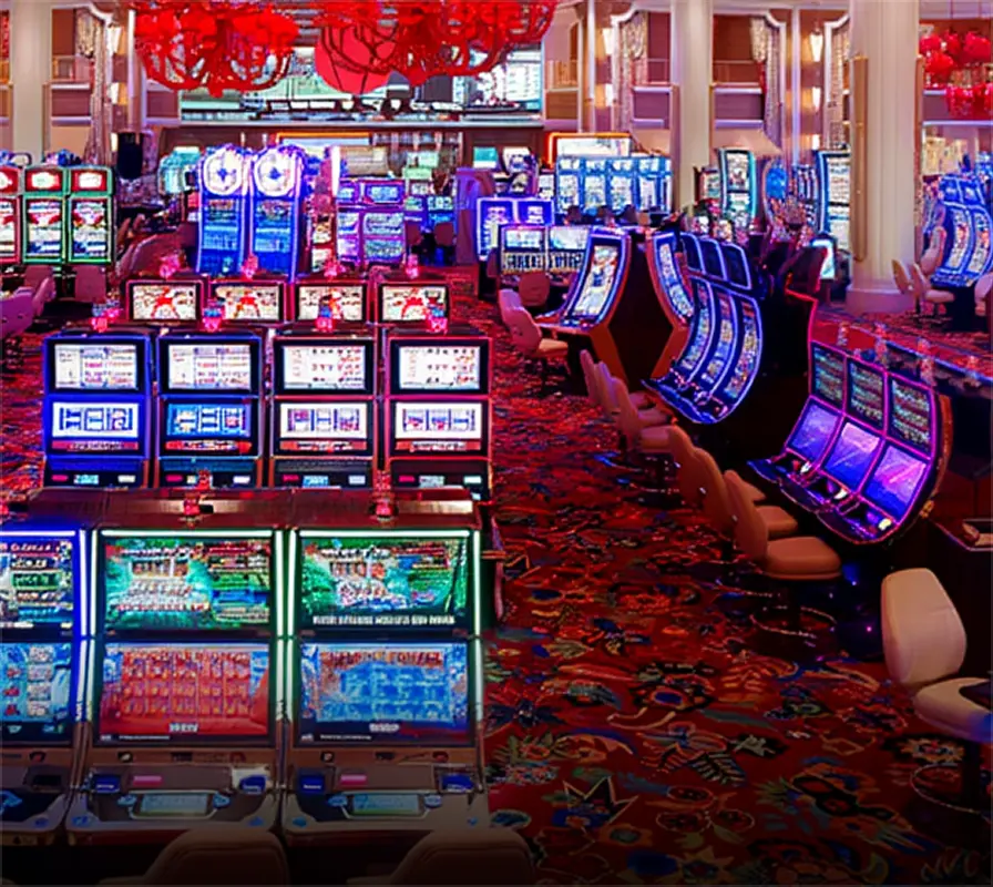 Interior of a casino with rows of illuminated slot machines and colorful carpet.