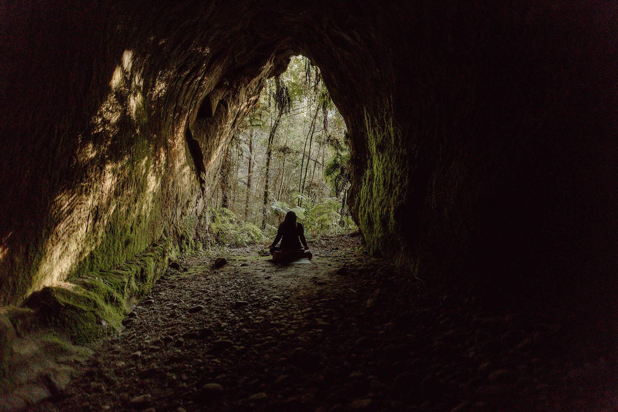 woman sitting in cave in forest new zealand