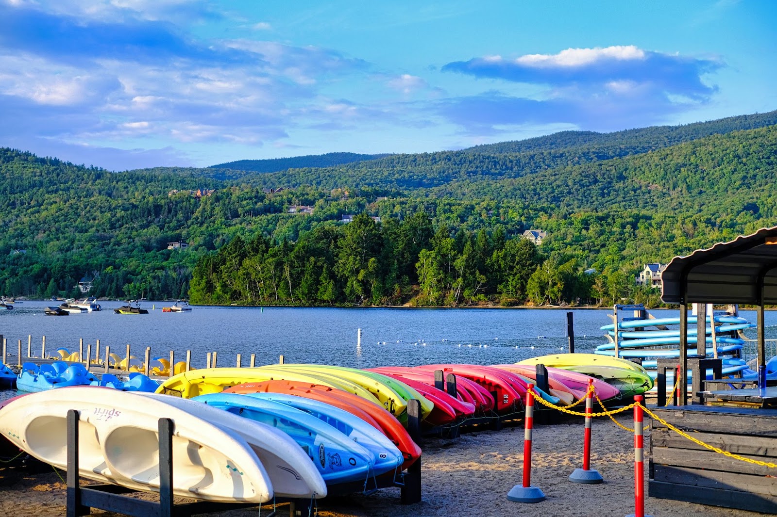 Row of colorful kayaks at a mountainous lake.
