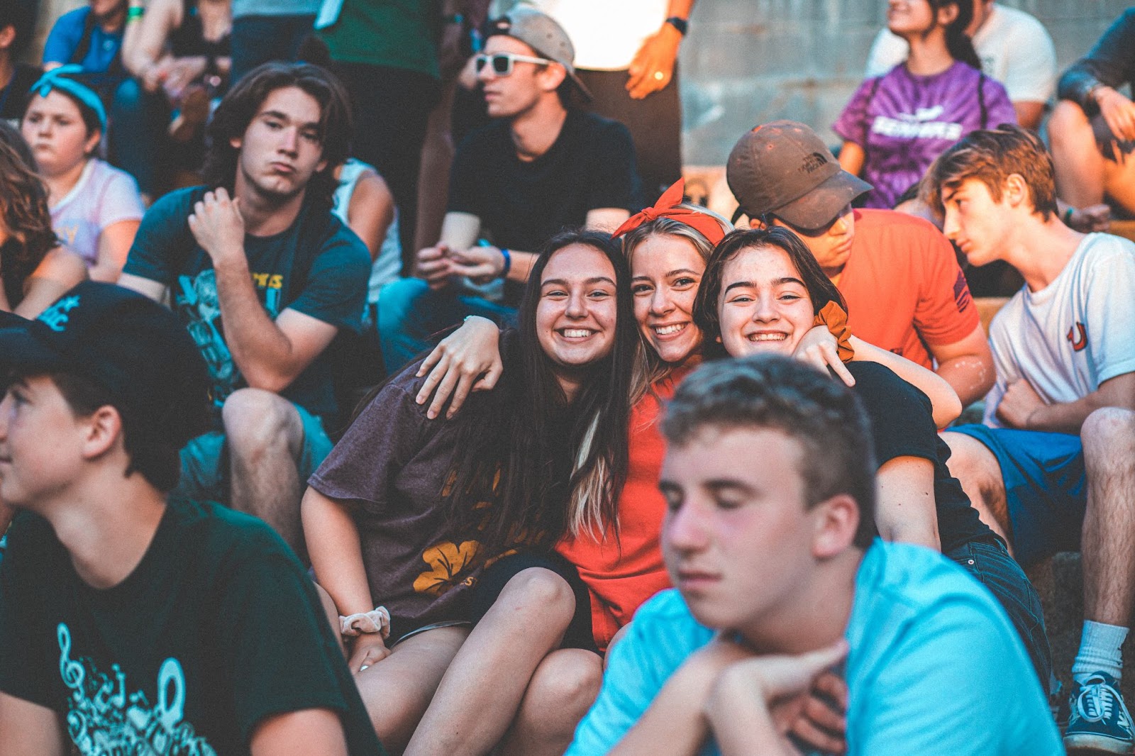 Group of female campers embracing and smiling amongst a crowd.