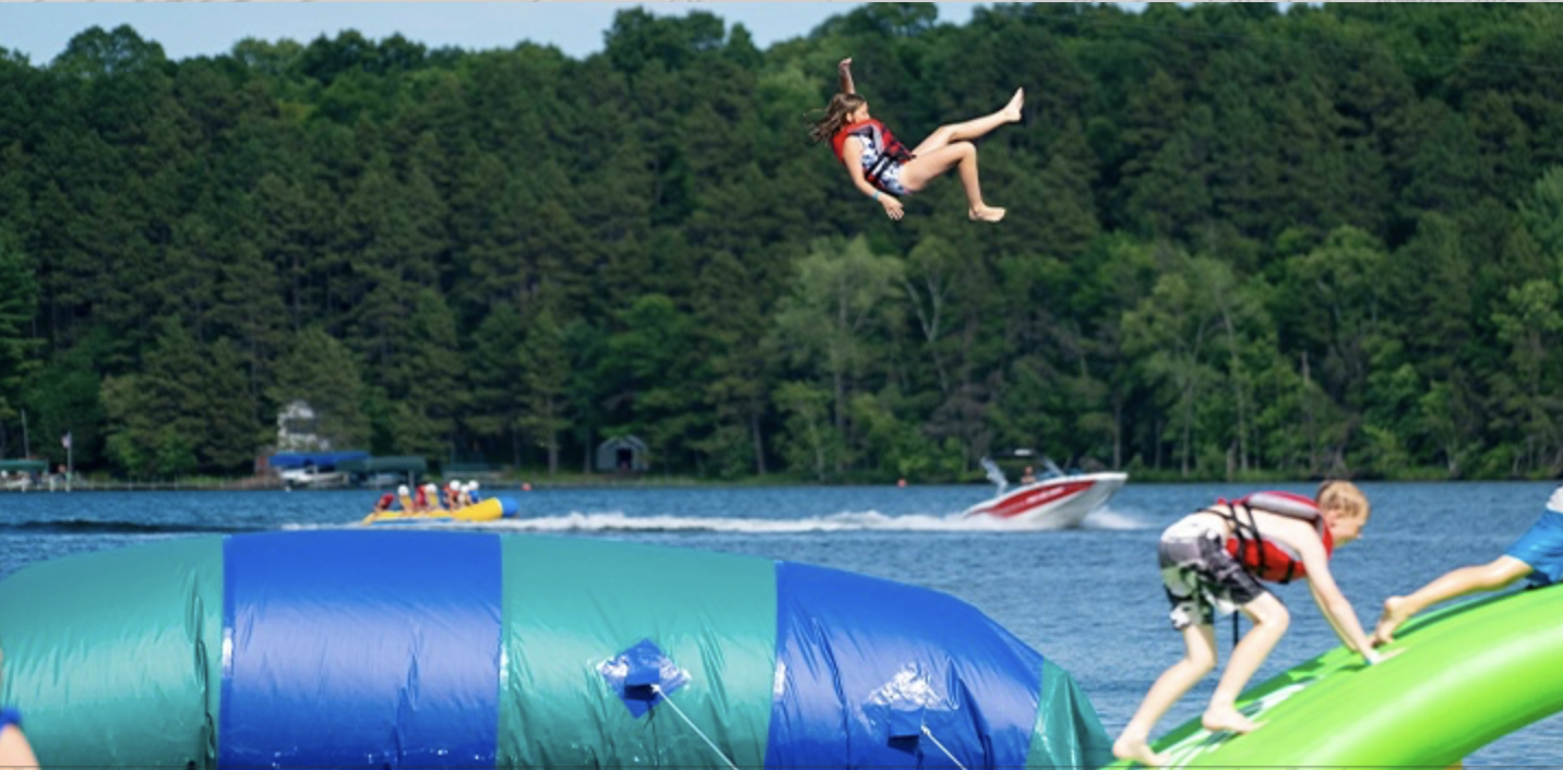 Campers playing on an inflatable water obstacle course.