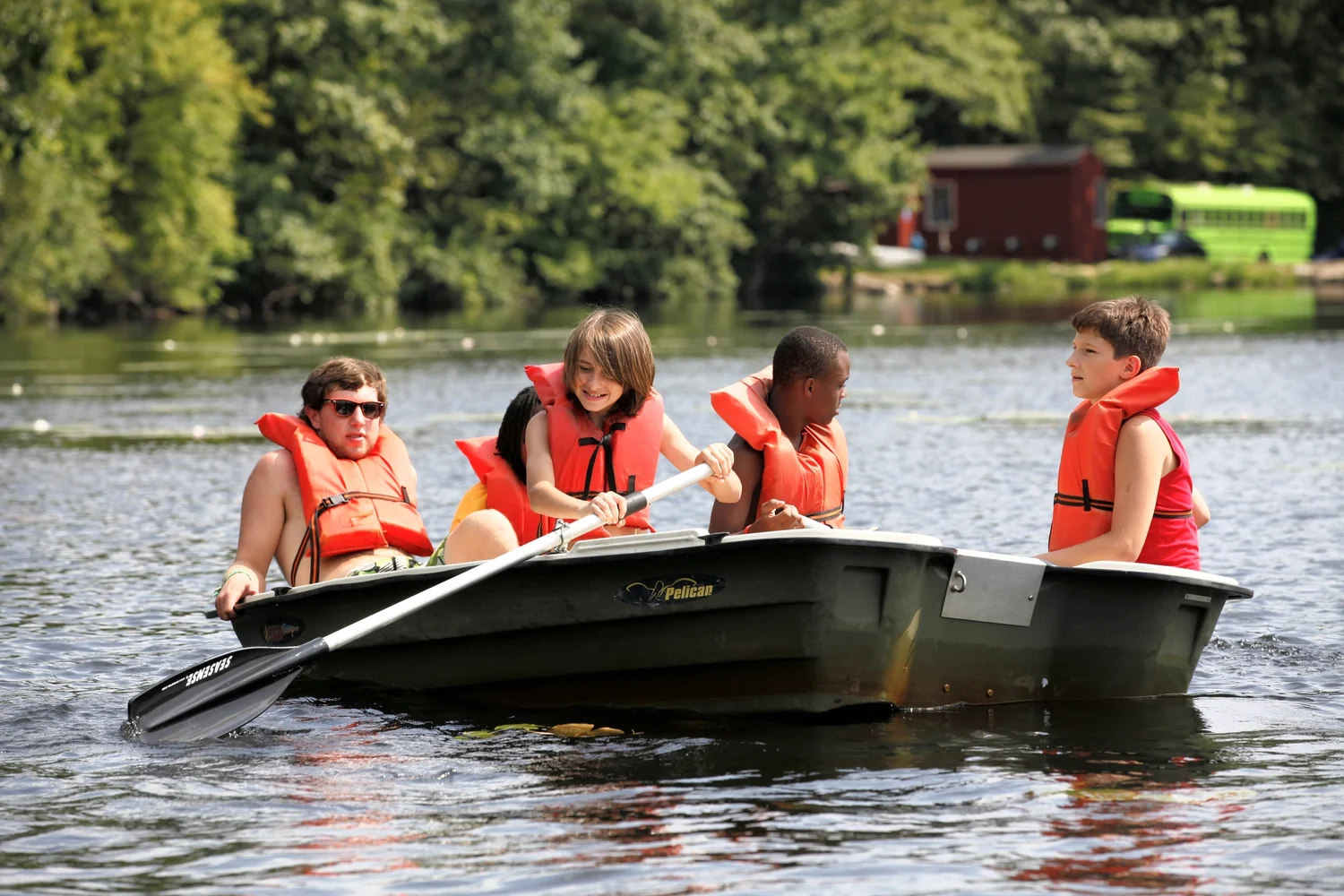 Campers and a counsellor at Camp Vacamas rowing a boat on the lake