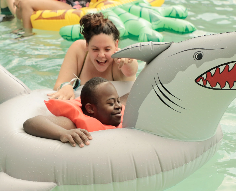 Camp counsellor and camper at Camp Anne playing on an inflatable pool toy