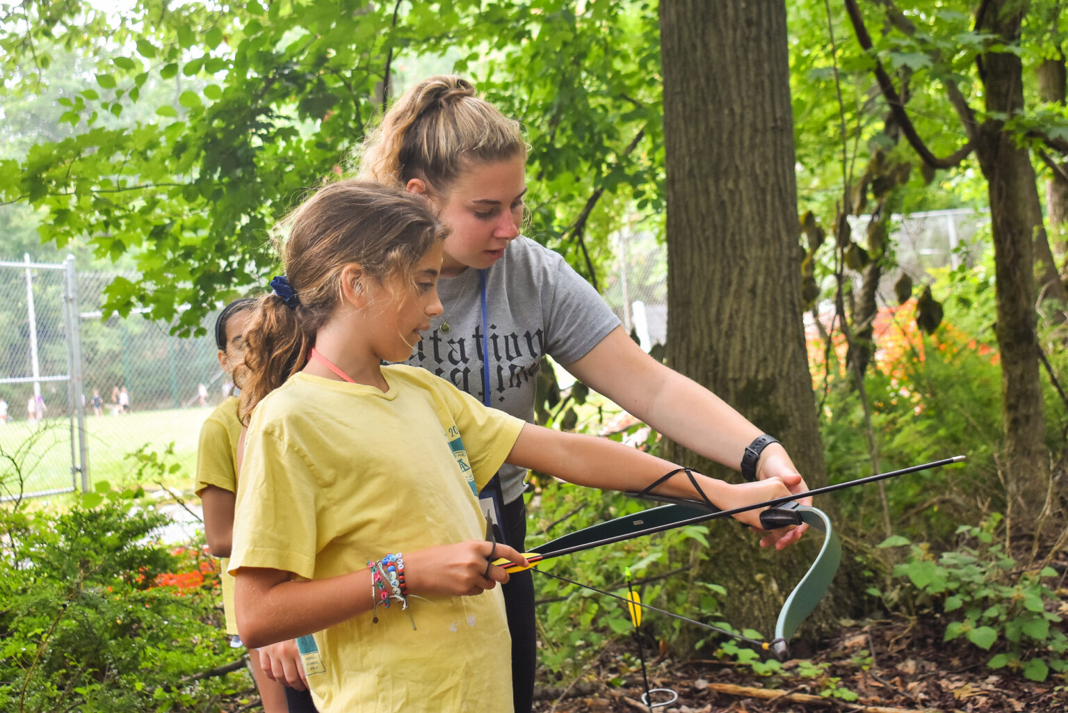 A camp counsellor shows a camper at Camp Louise how to hold a bow and arrow