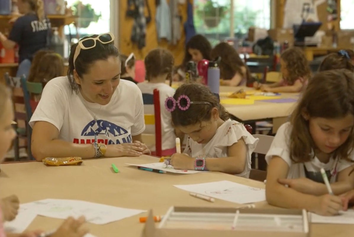 AmeriCamp Camp counsellor supervising campers as they draw and colour