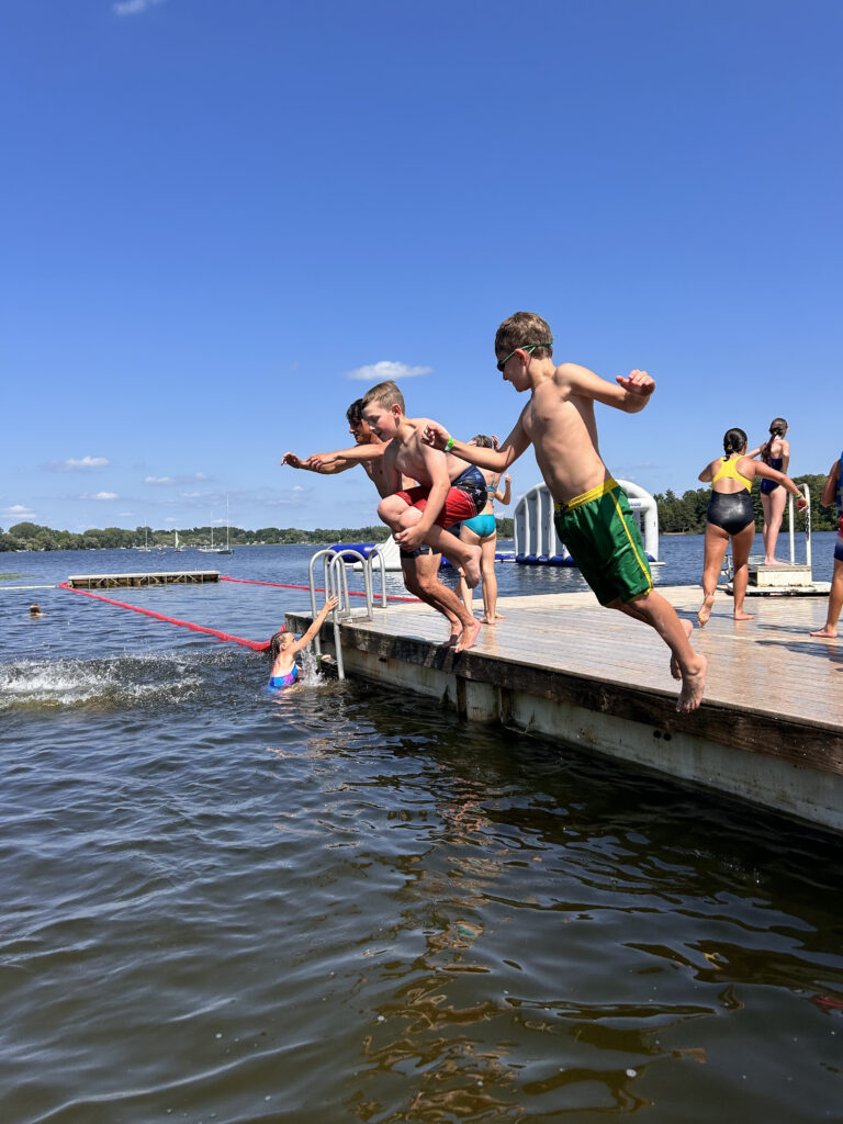 Campers at YMCA Storer Camps jumping from a pier into the lake
