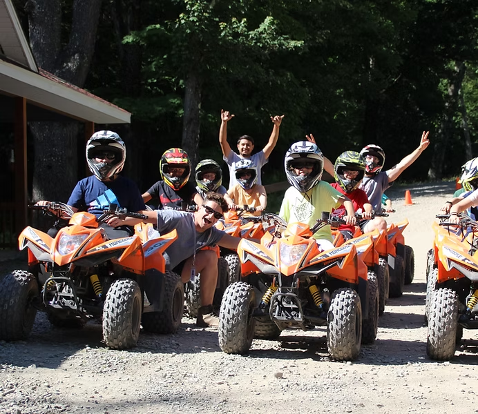 Campers and camp counsellors at Camp Chipinaw riding ATVs