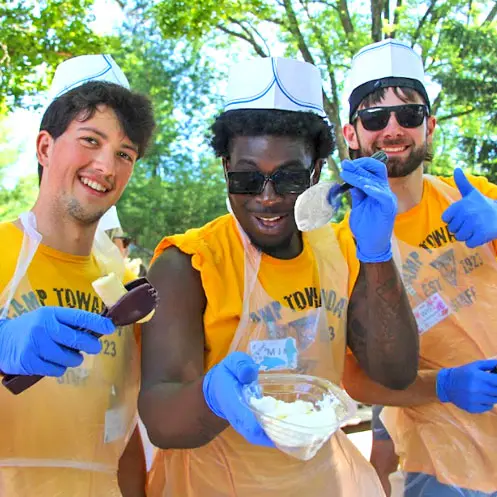 Camp counsellors at Camp Towanda baking in chefs hats and plastic aprons