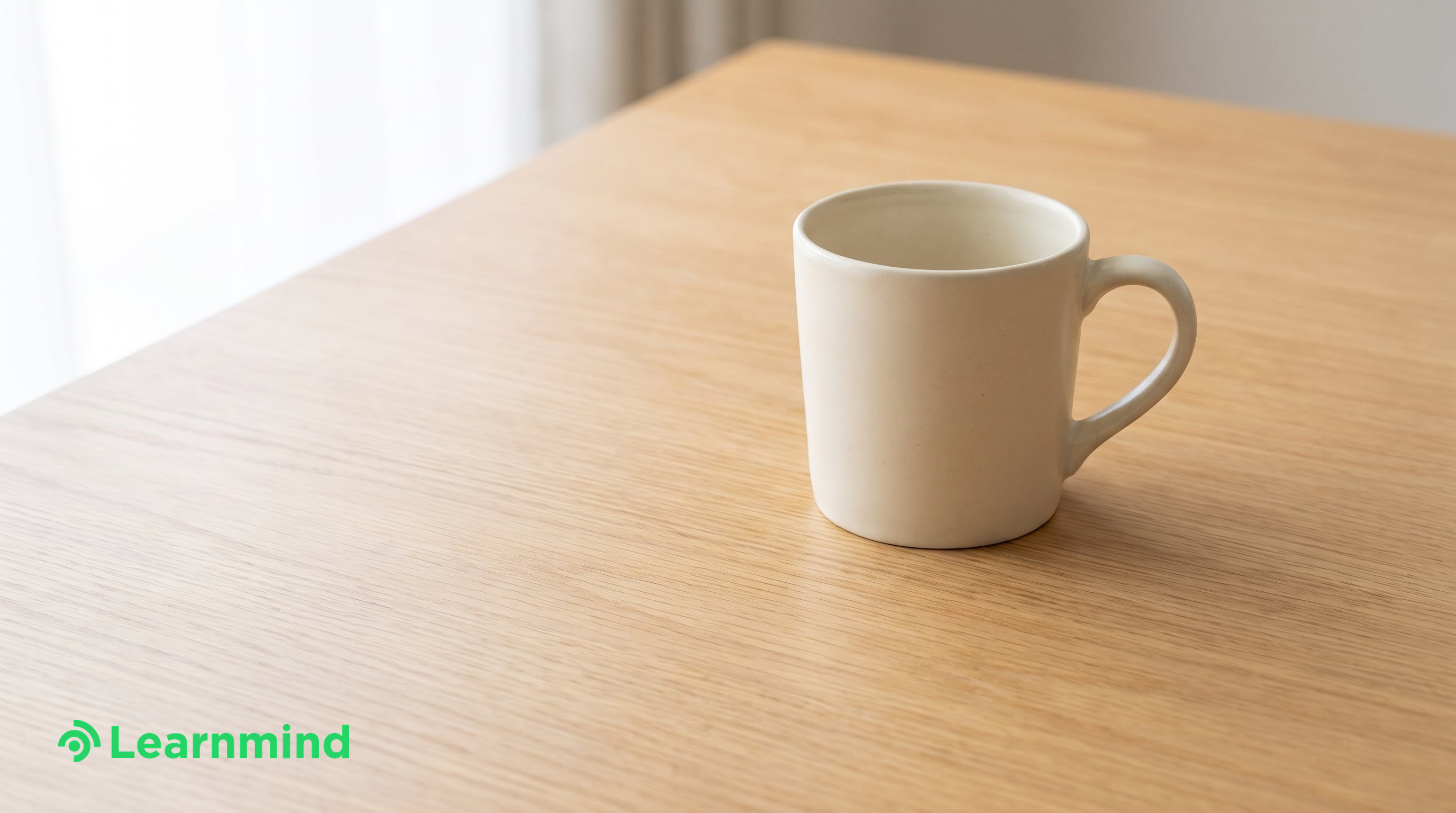 single cream ceramic mug on empty wood desk, bright daylight