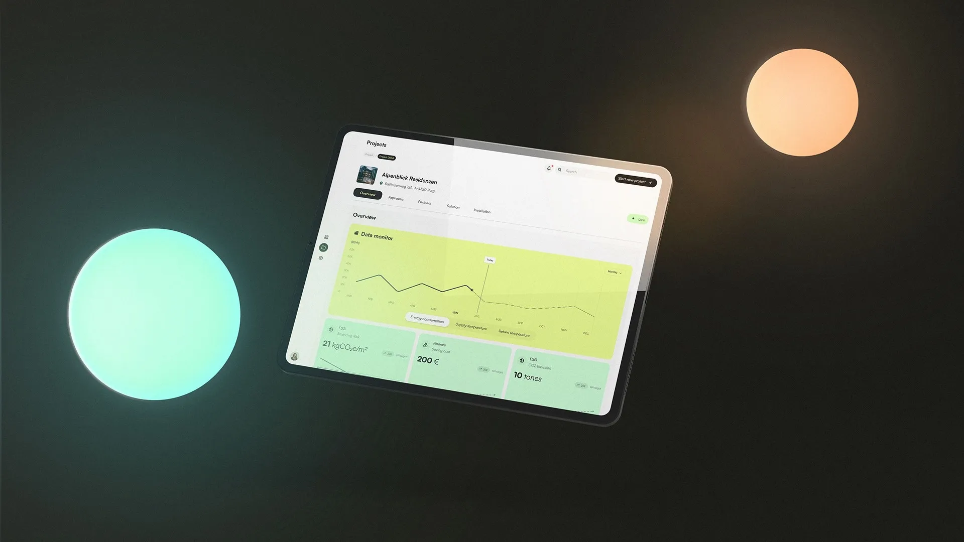 Tablet mit Benutzeroberfläche eines Projekt-Dashboards auf schwarzem Hintergrund mit zwei leuchtenden Lichtkreisen; angezeigt sind Diagramme zu Energieverbrauch, Temperaturen und CO2-Werten für das Projekt „Alpenblick Residenzen“.