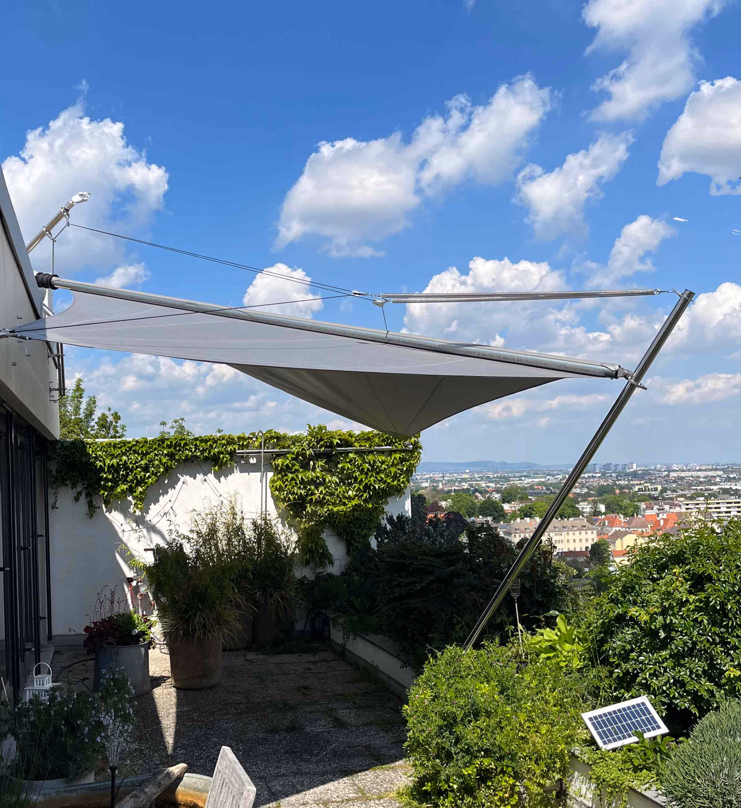 A cozy balcony with views over Vienna, the seating area is protected from sun and rain by a SunSquare awning.