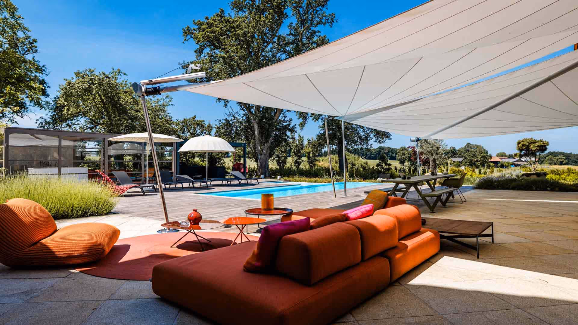 Two SunSquare shade sails protect the dining area and the stylish outdoor sofa by Paola Lenti. The adjacent pool invites you to cool off.