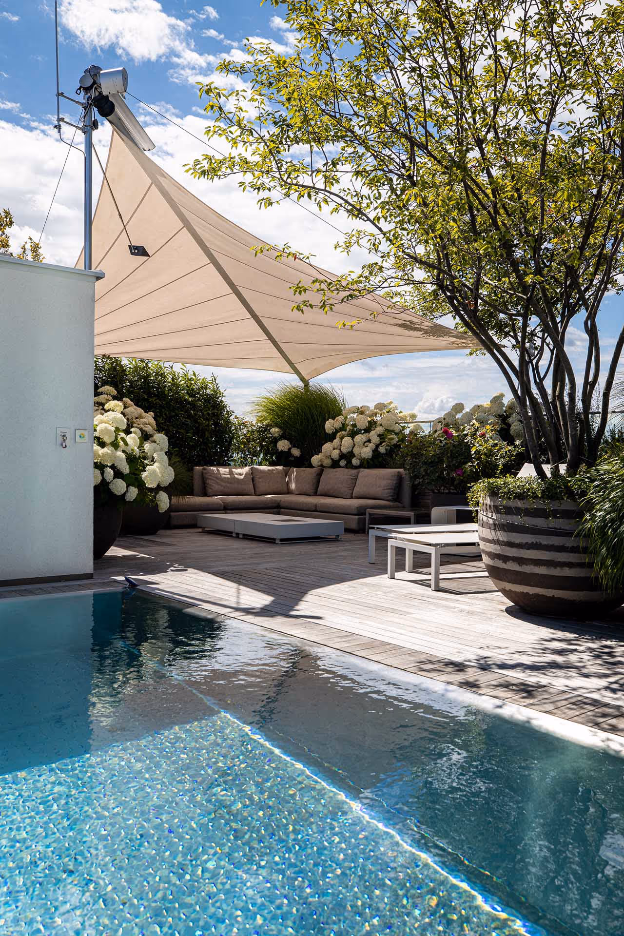 Das Gemeinschaftsprojekt von Kramer und Kramer und SunSquare verwandelte eine urbane Dachterrasse in einen grünen Dachgarten mit üppiger Bepflanzung, einem eleganten Edelstahlpool und großzügiger Beschattung durch maßgeschneiderte SunSquare-Sonnensegel.