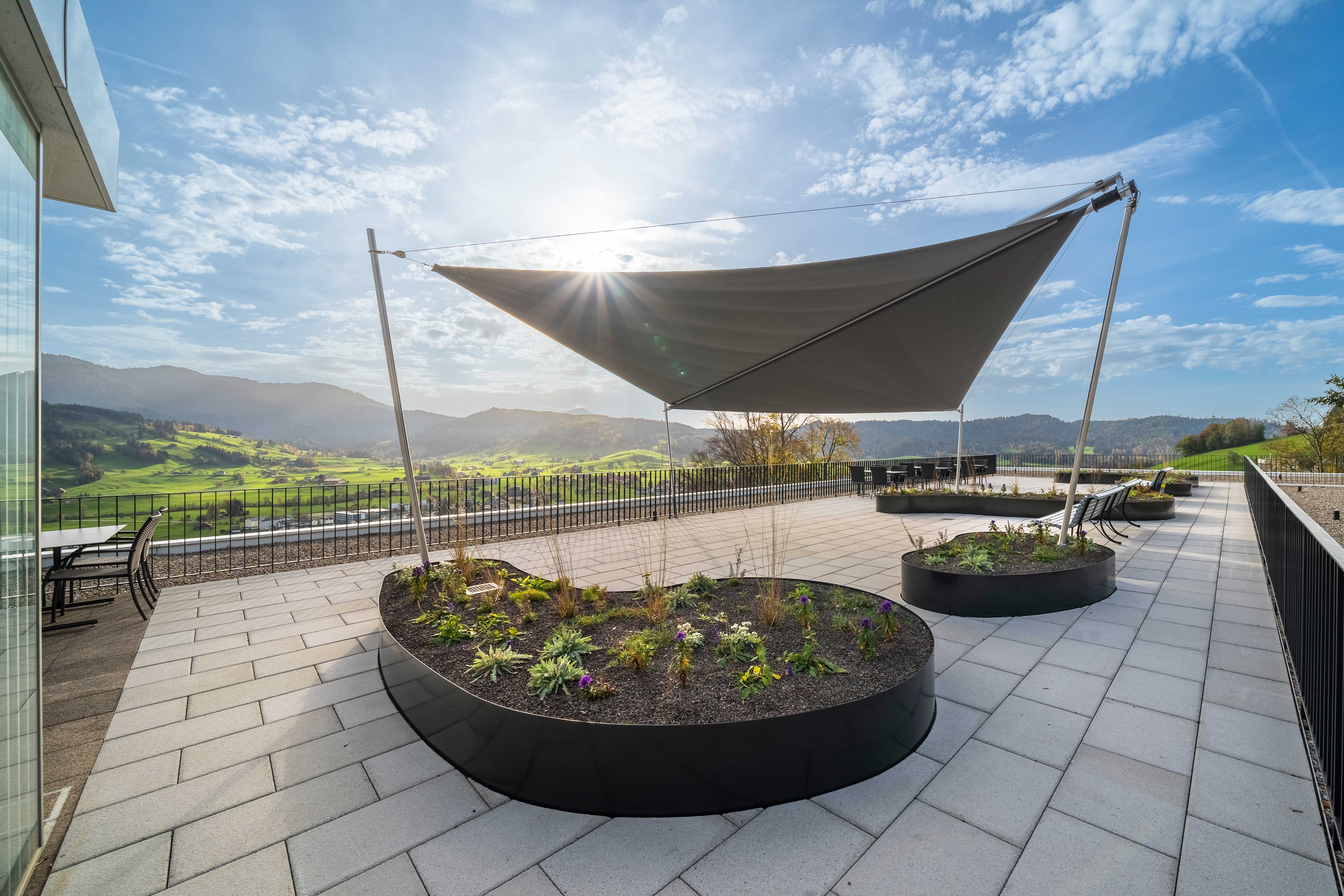 Die Dachterrasse der Pflegeeinrichtung - stilvoll mit Pflanzentrögen und SunSquare Segel ausgestattet.