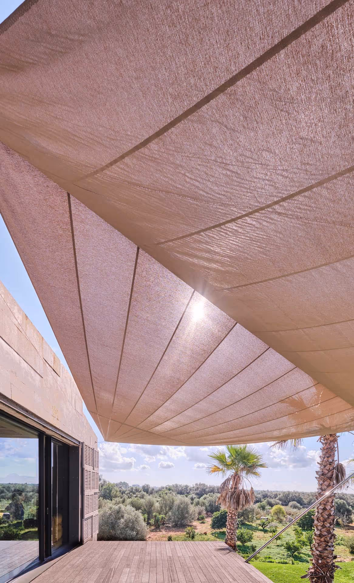 Das elegante Segel verwandelt den tropischen Garten mit Palmen und mediterranen Büschen in einen idyllischen Ort zum Entspannen.