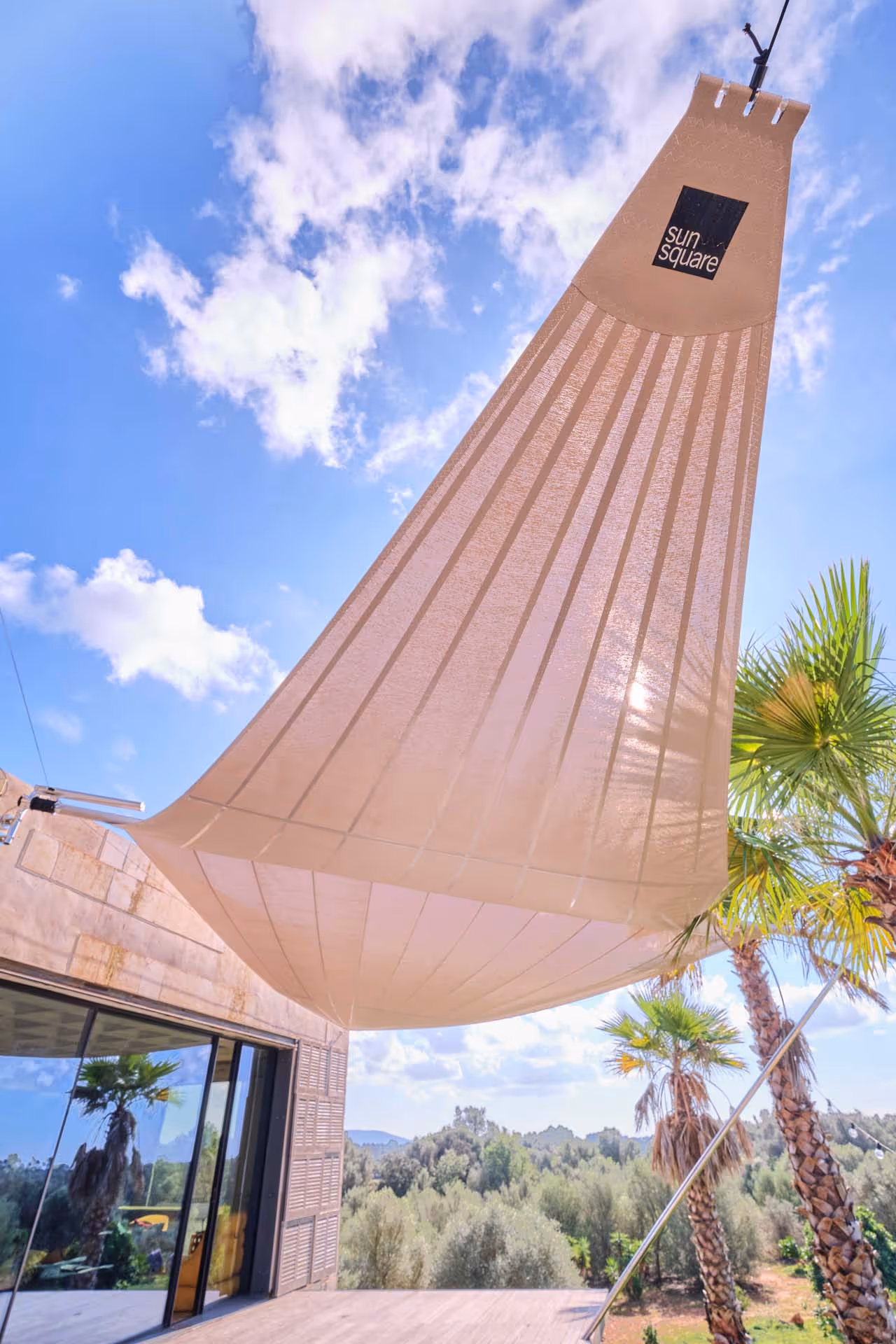 Das elegante Segel verwandelt den tropischen Garten mit Palmen und mediterranen Büschen in einen idyllischen Ort zum Entspannen.