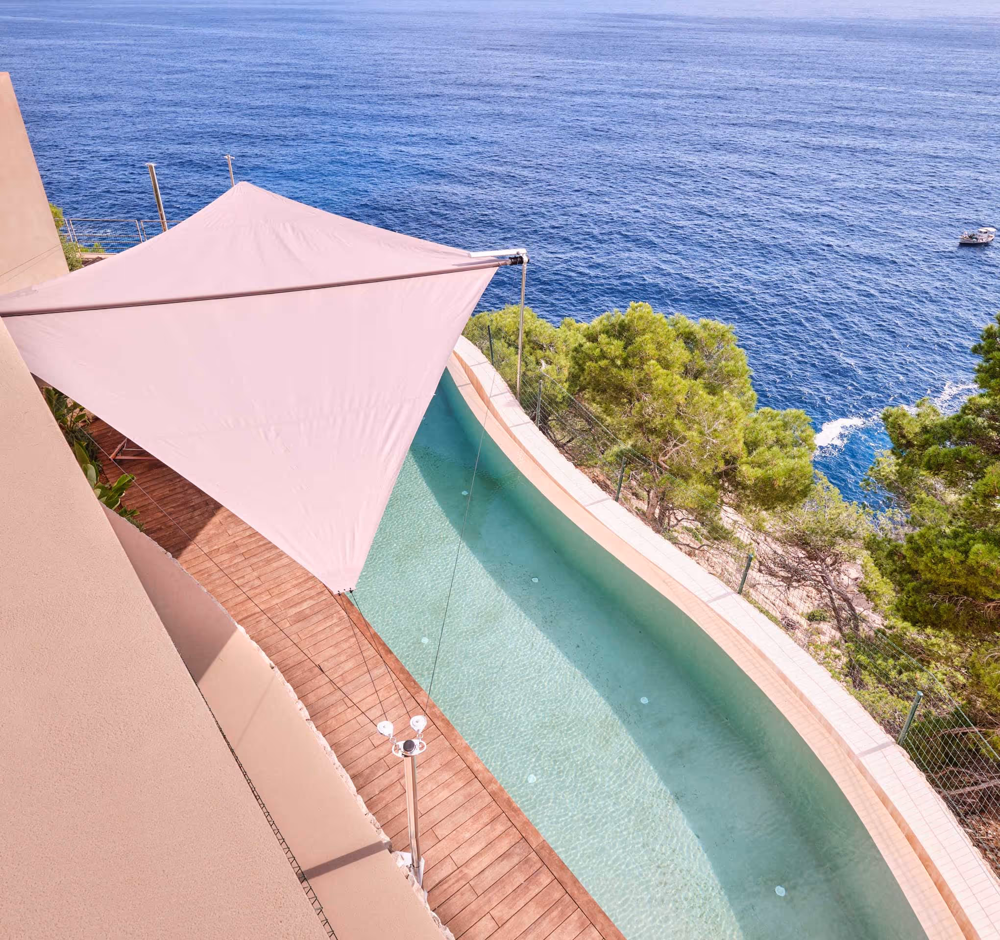 A sun sail stretches elegantly over an infinity pool seamlessly integrated into Mallorca’s rugged coastline. The effect is mesmerizing — it feels as though you're swimming one level above the sea. Breathtaking views unfold: dramatic cliffs, wild trees, and the endless expanse of the Mediterranean.itypool, der in die Steilküste von Mallorca integriert wurde, es entsteht der Eindruck, man schwimmt eine Etage über dem Meer. Atemberaubende Aussicht auf Felsen, wilde Bäume und das weite Meer.