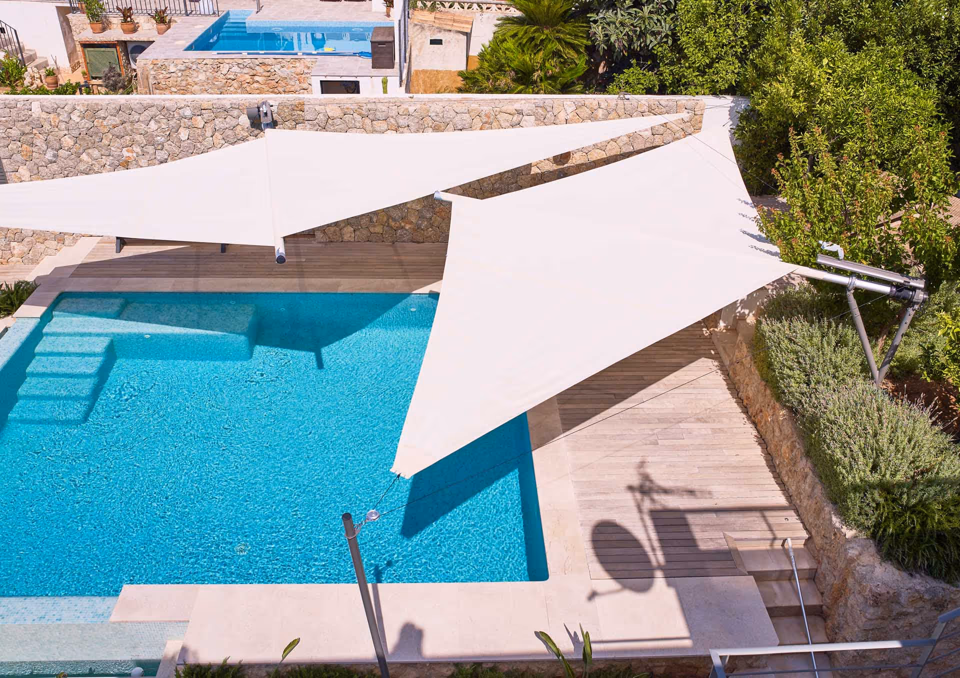 Freikragende SunSquare SQK-Cantilever Sonnensegelanlage überspannt elegant den Poolbereich ohne störende Stützen.